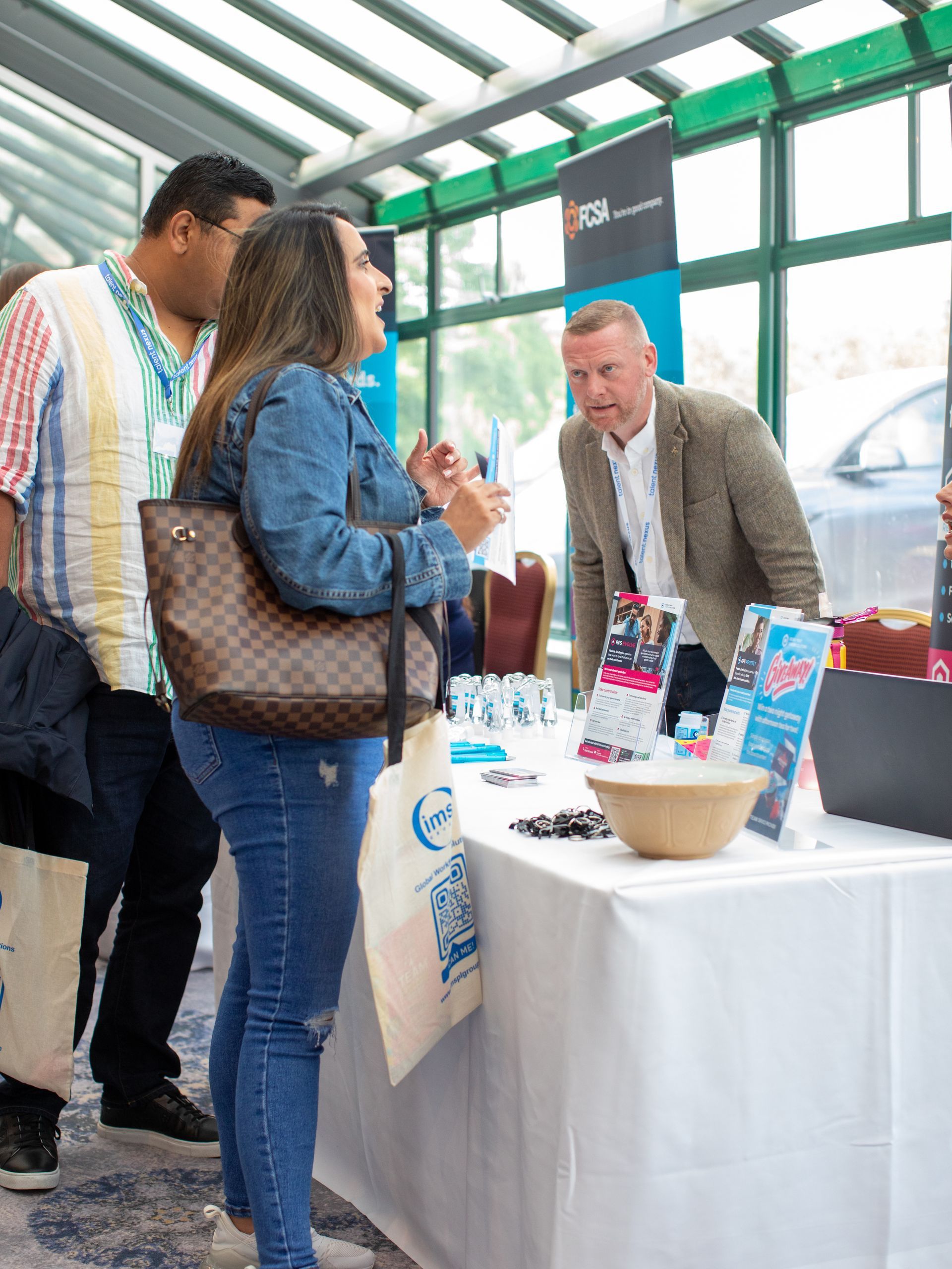 A group of people are standing around a table at a convention.