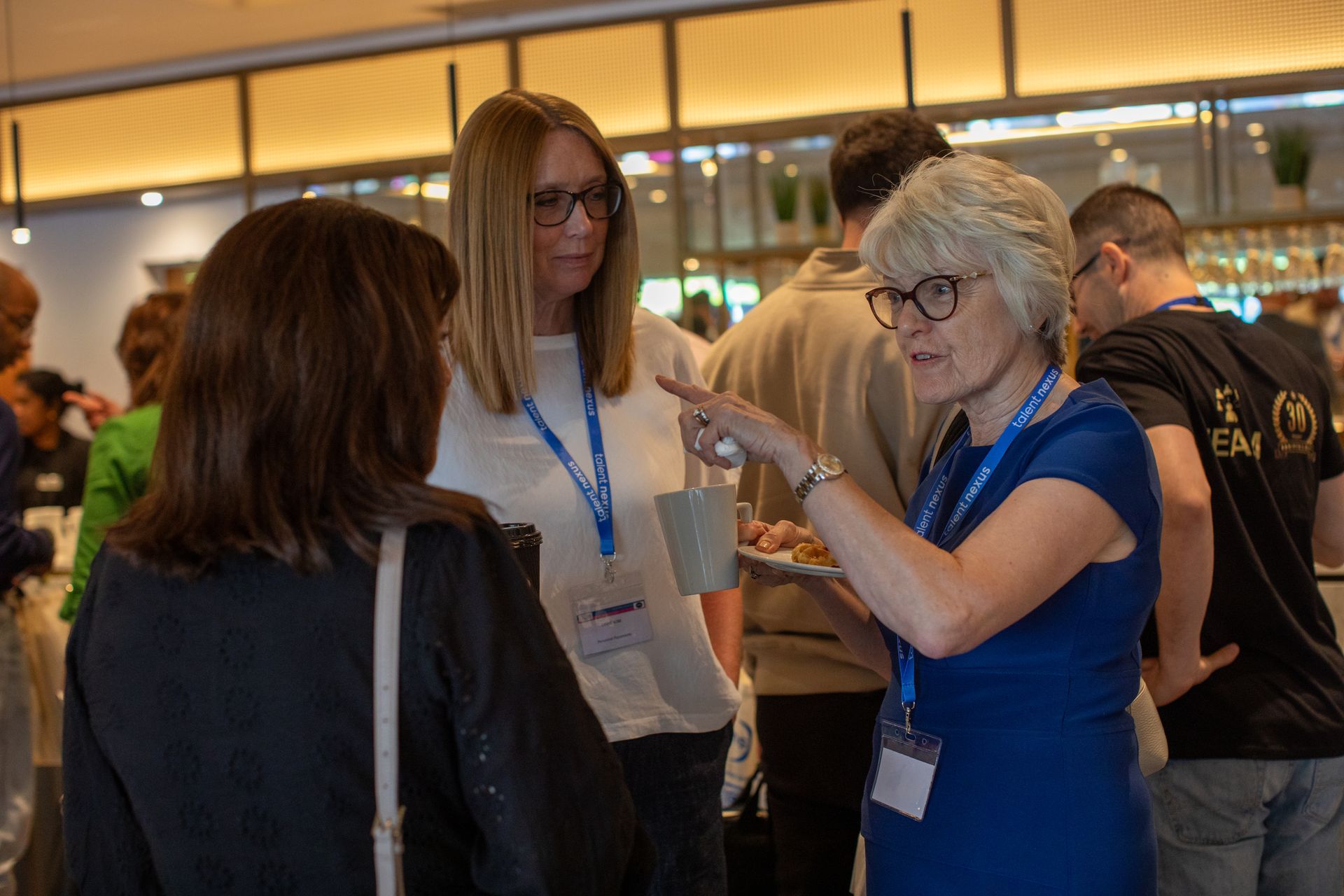 A group of people are standing in a room talking to each other.