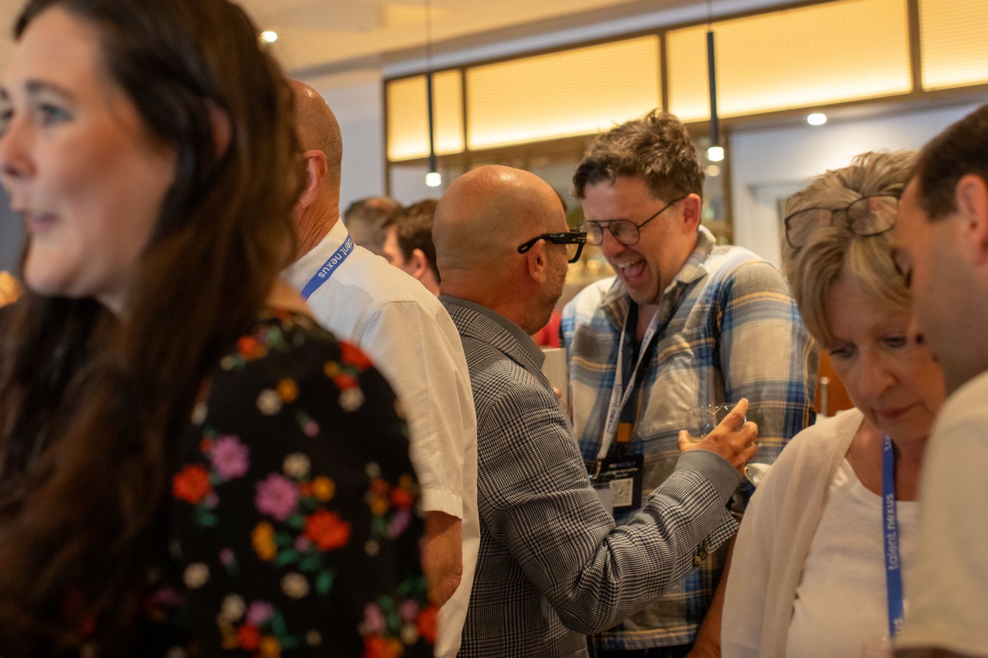 A group of people are standing in a room talking to each other.