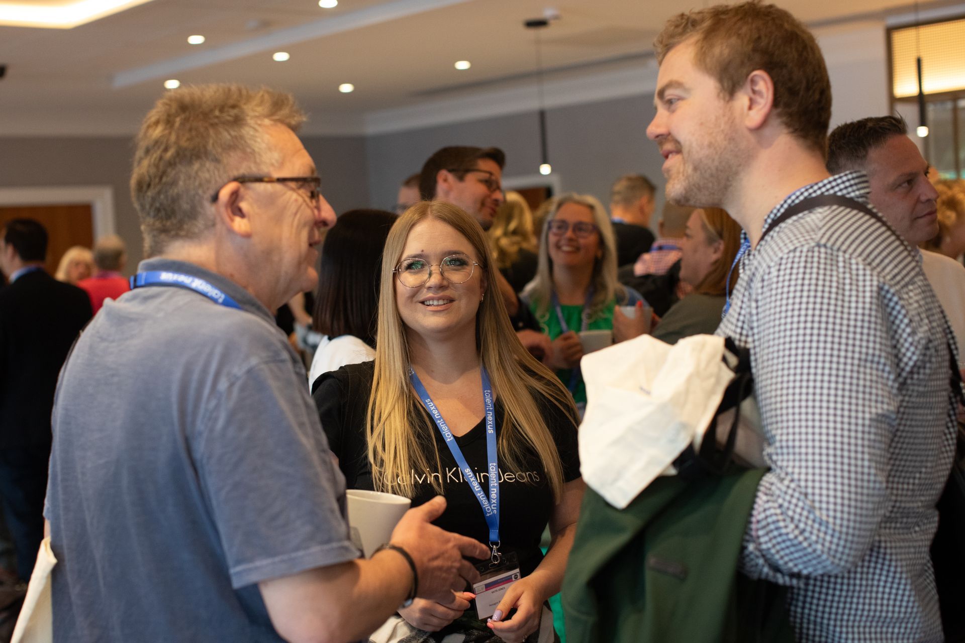 A group of people are standing in a room talking to each other.
