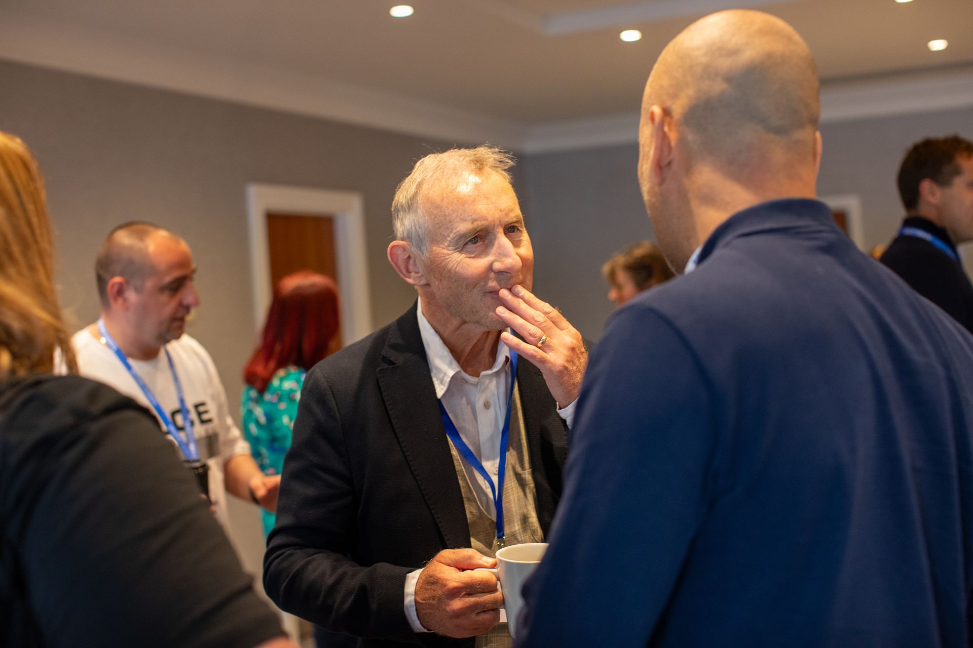 A group of men are standing around talking to each other in a room.