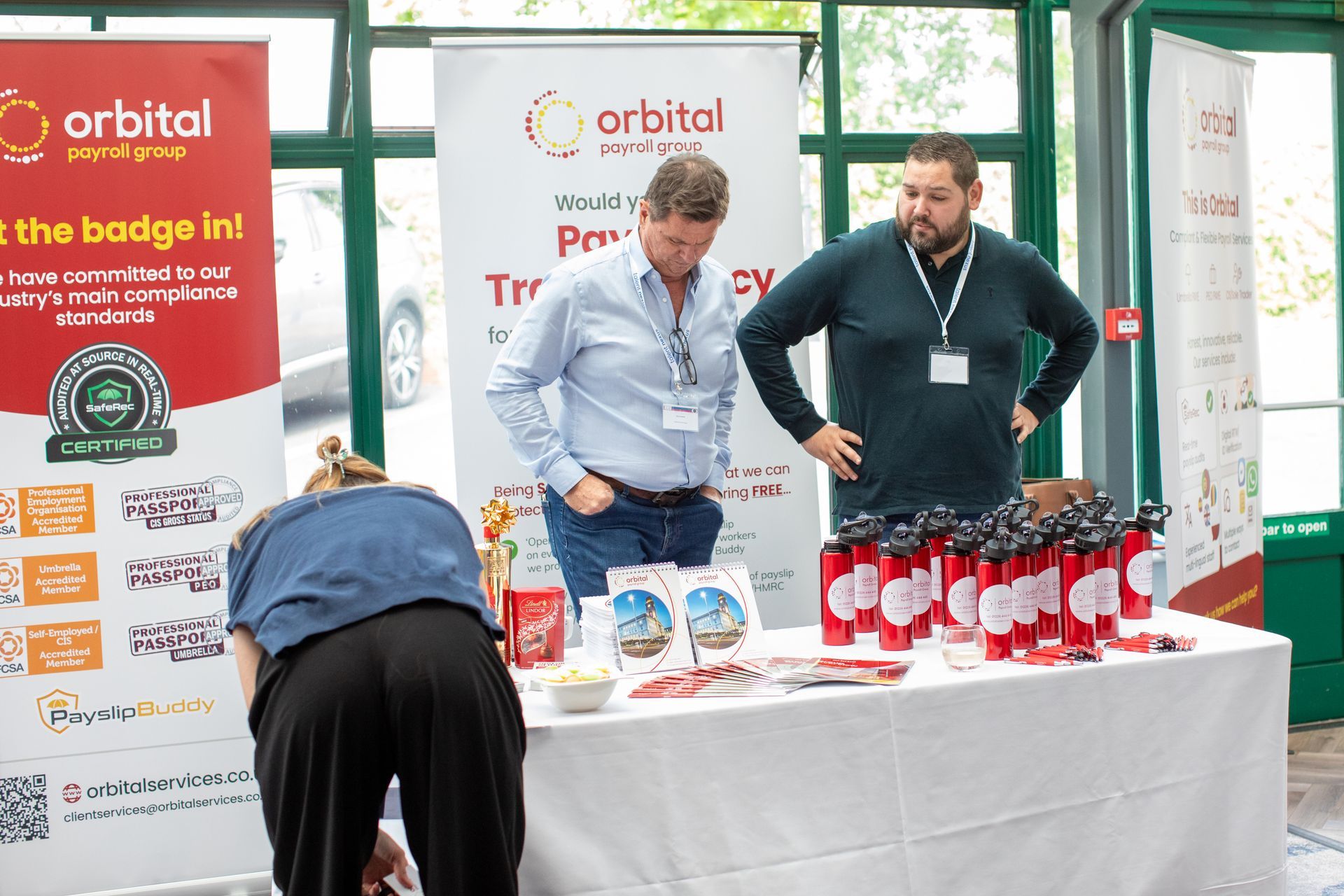 A group of people are standing around a table with a sign that says orbital.