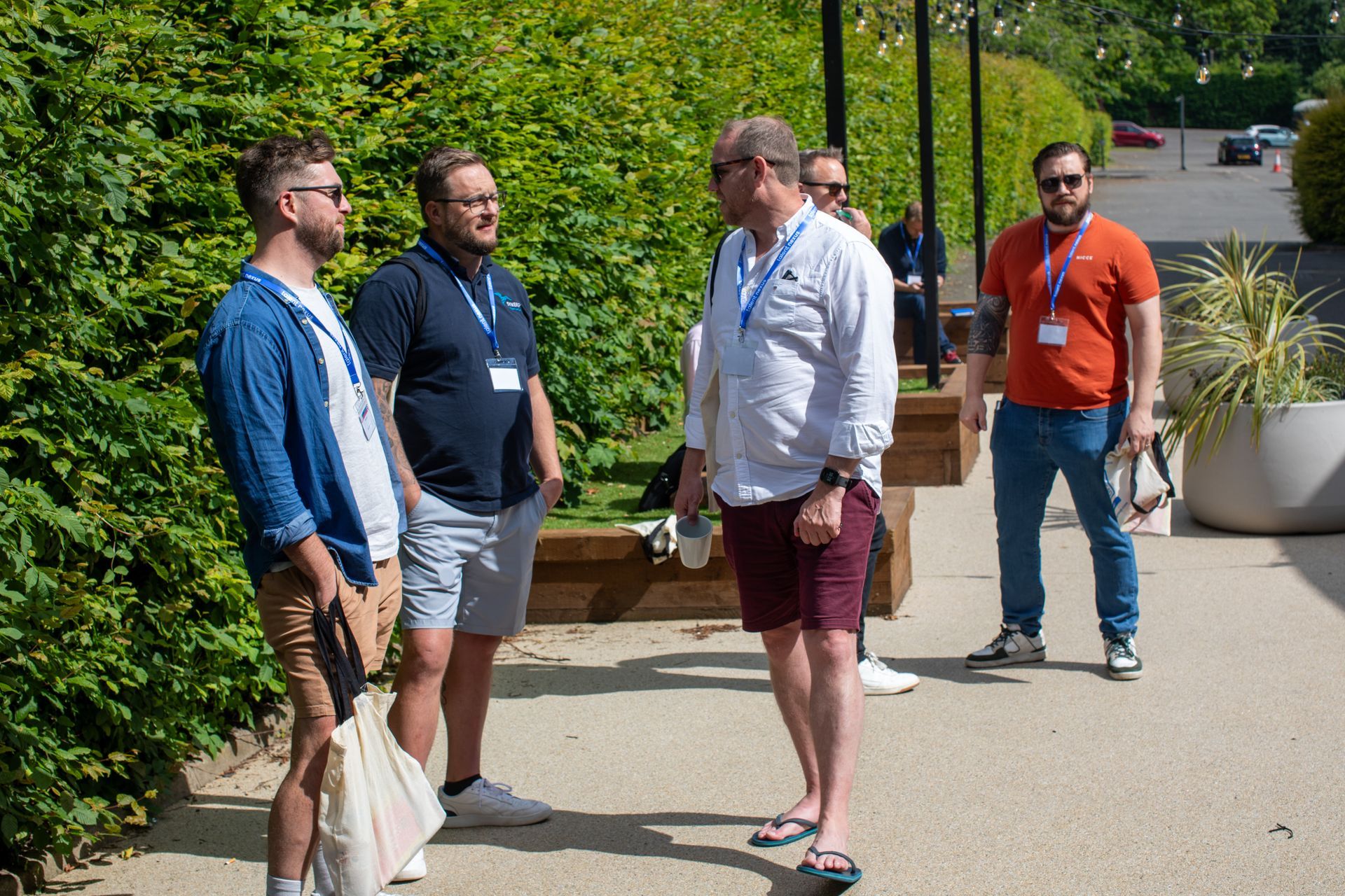 A group of men are standing on a sidewalk talking to each other.