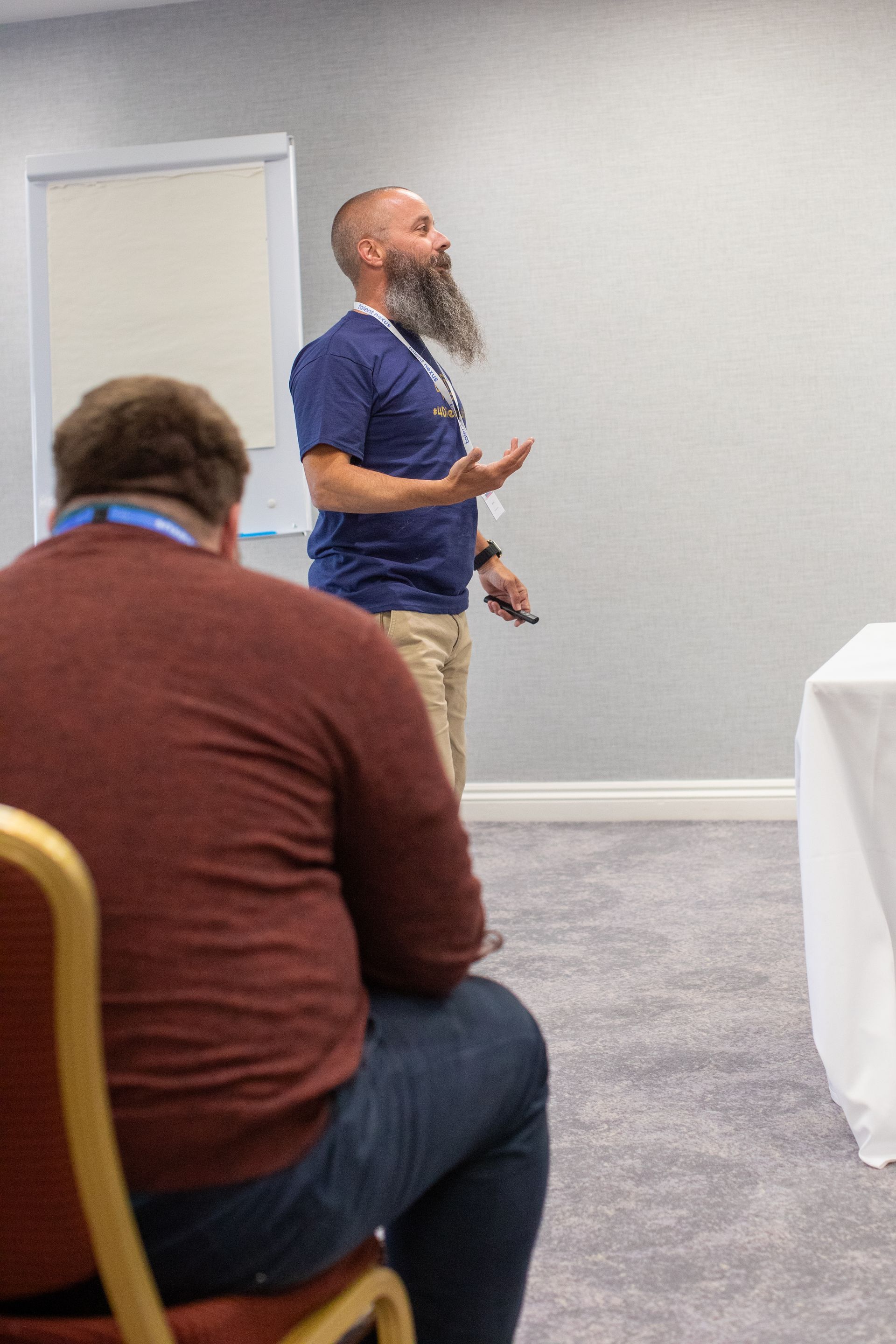 A man with a beard is giving a presentation to a group of people sitting in chairs.
