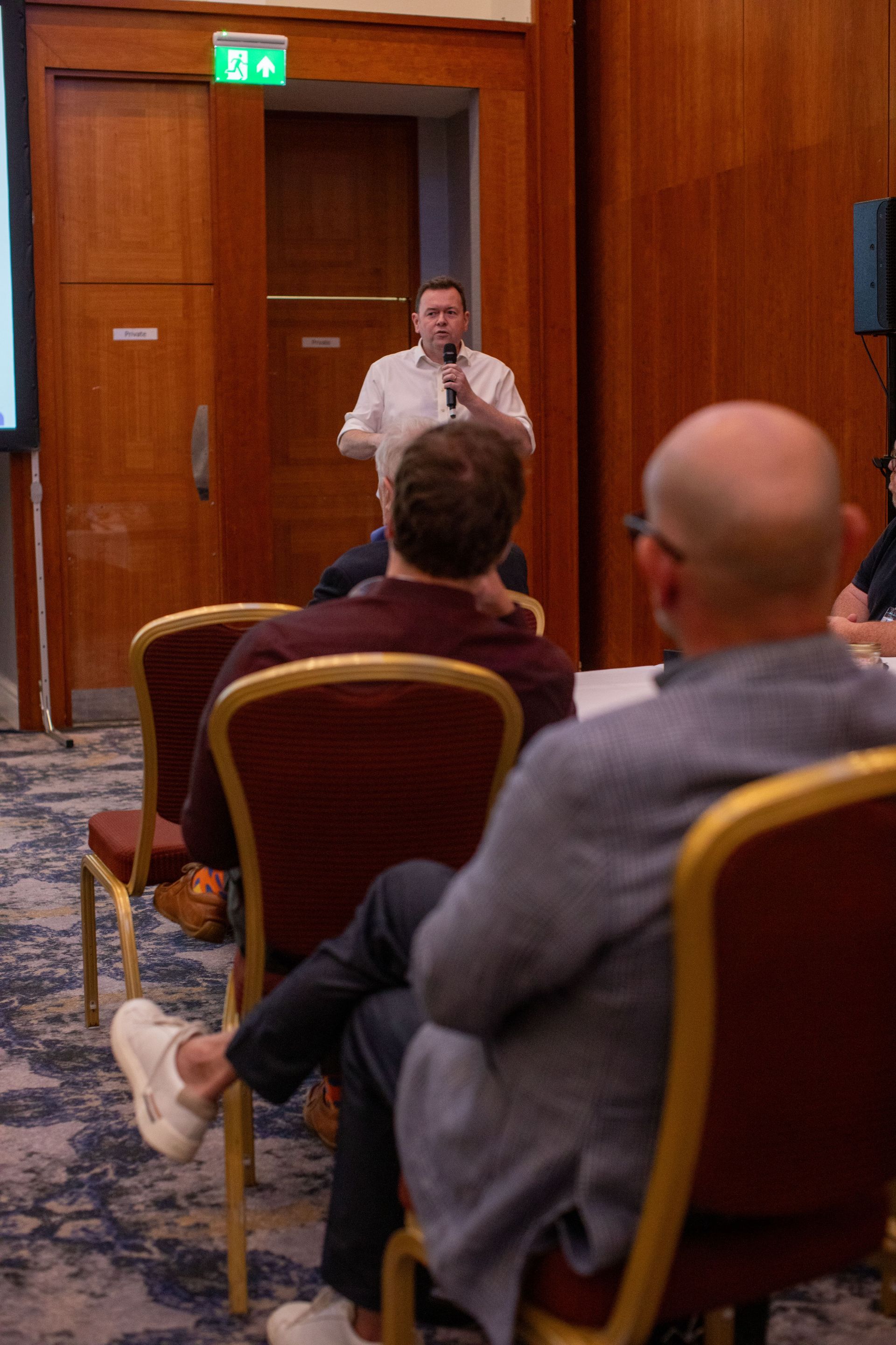 A man is giving a presentation to a group of people sitting in chairs.