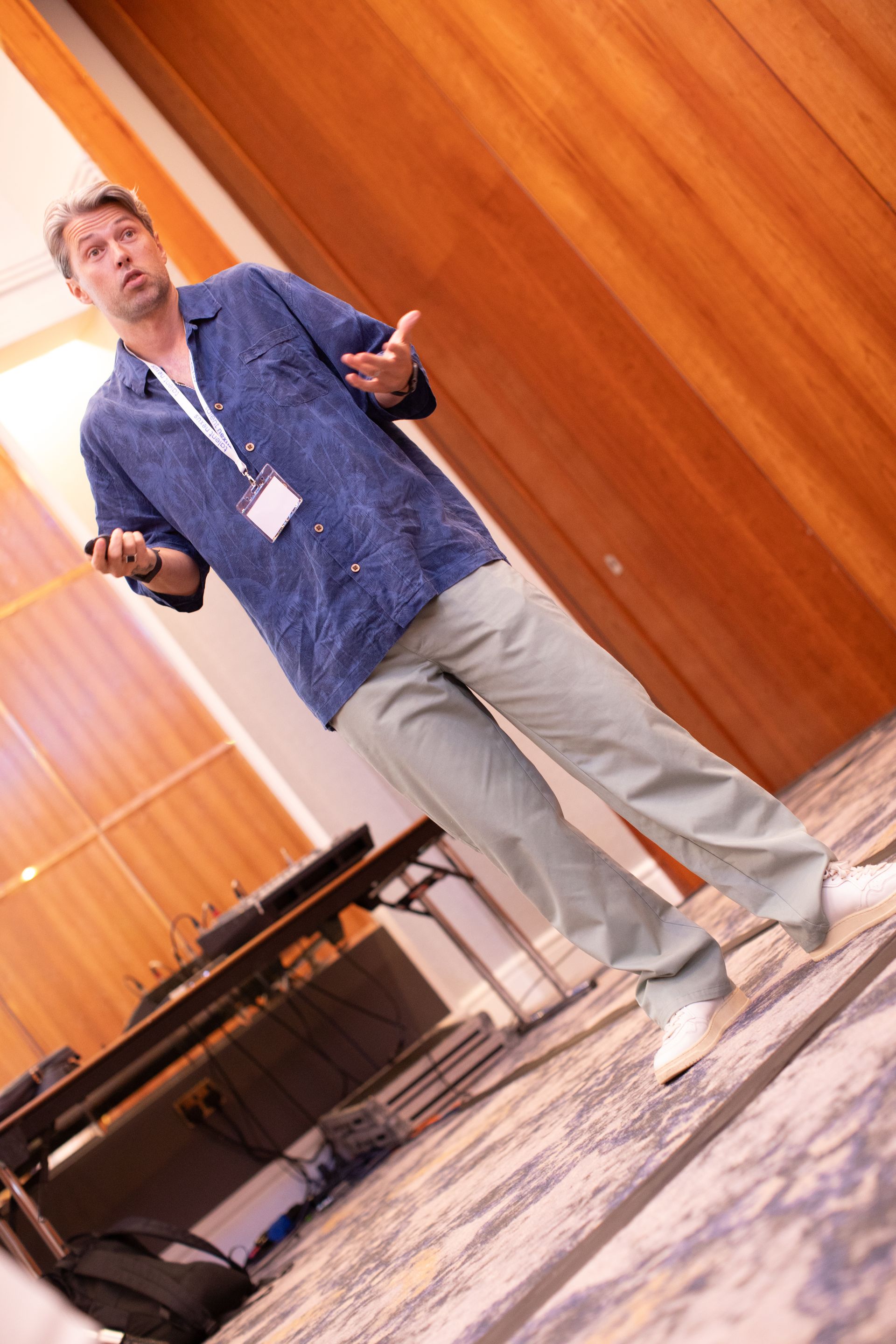 A man in a blue shirt is giving a presentation in a conference room.