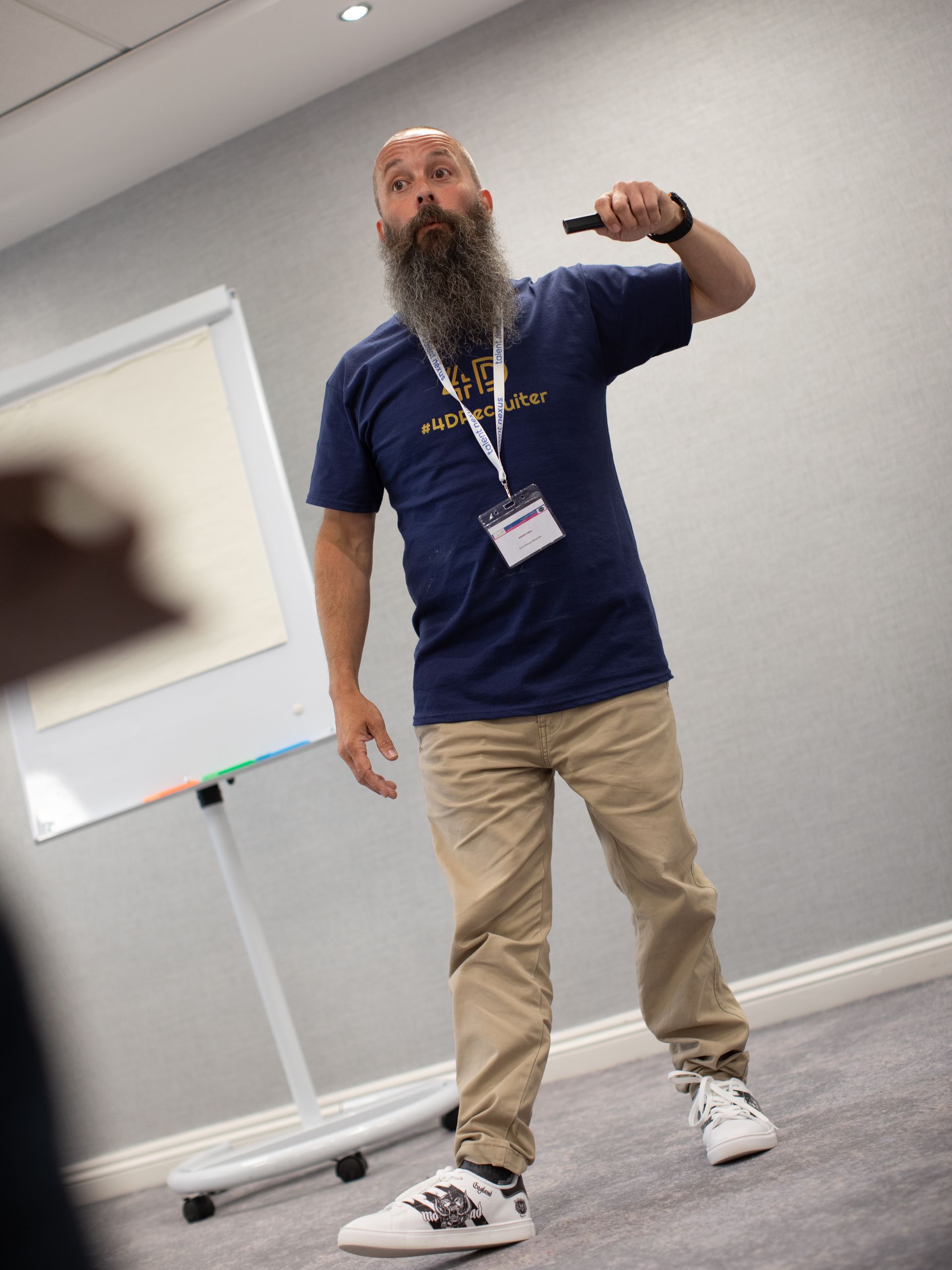 A man with a beard is standing in a room holding a microphone.