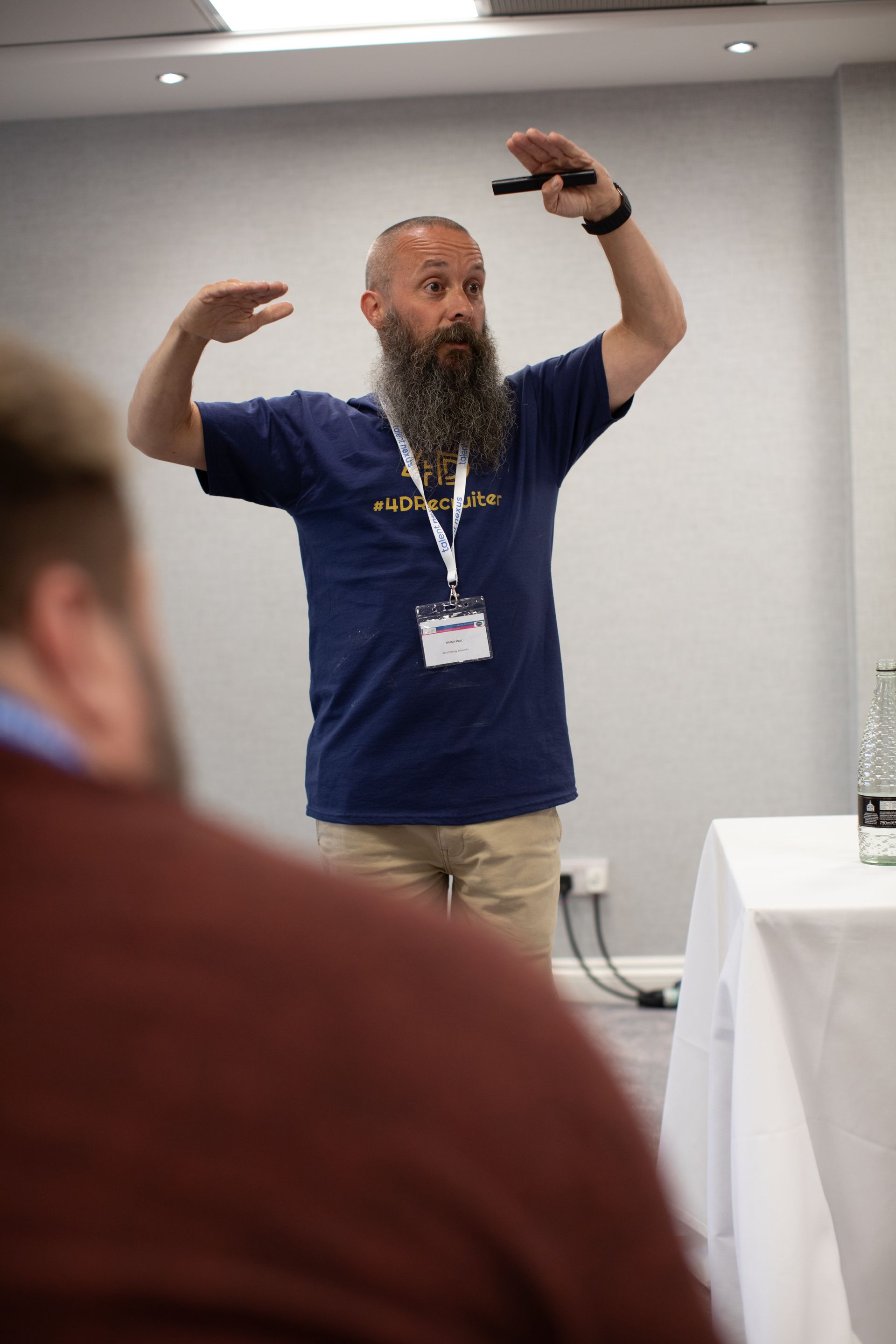 A man with a beard is giving a presentation in front of a group of people.