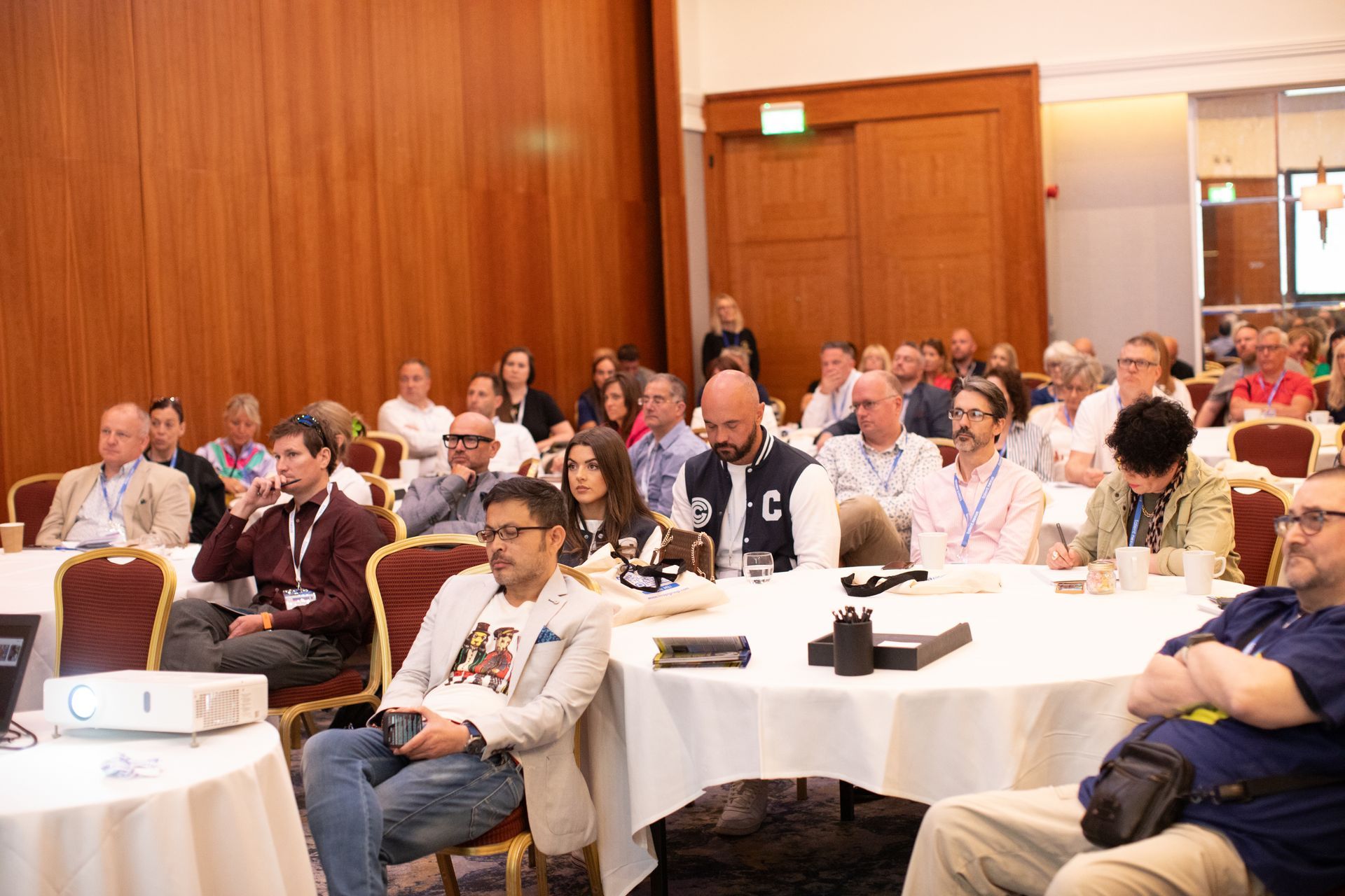 A group of people are sitting at tables in a conference room.