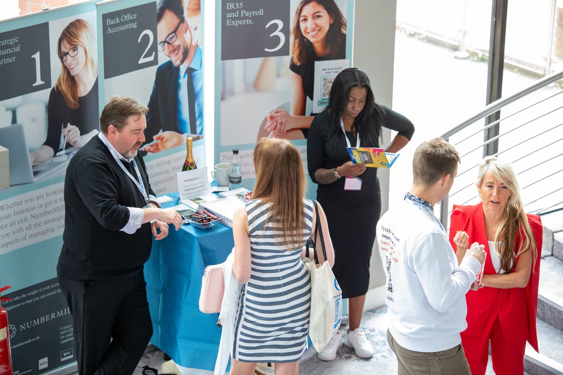 A group of people are standing around a table at a job fair.