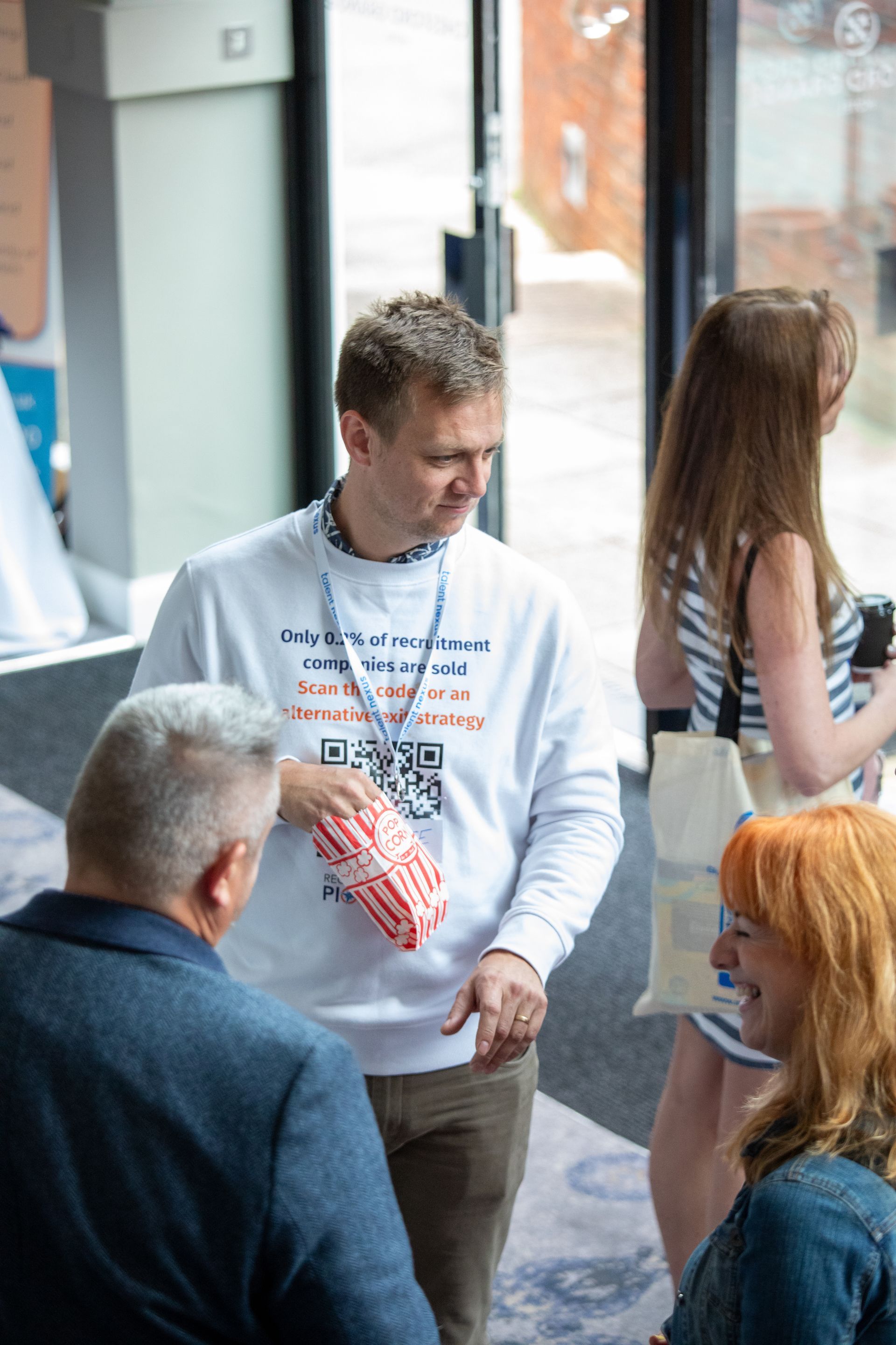 A group of people are standing in a room talking to each other.