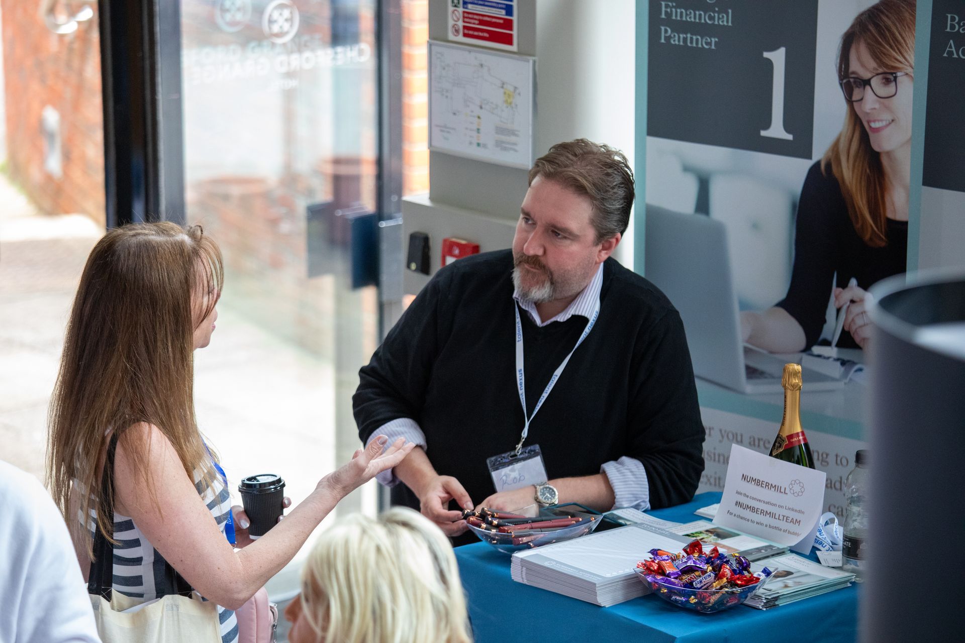 A man and a woman are sitting at a table talking to each other.