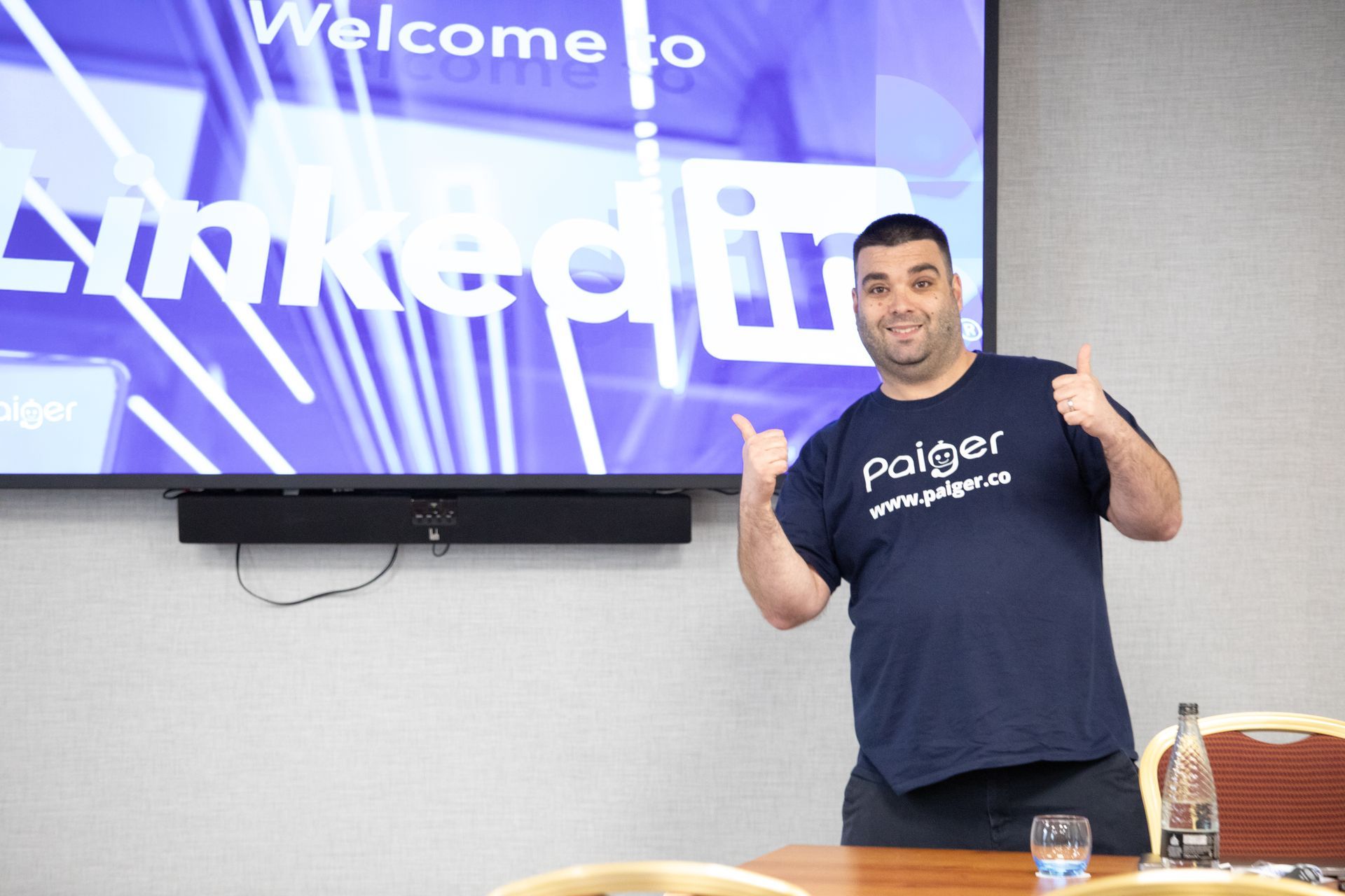 A man is giving a thumbs up in front of a screen that says welcome to linkedin