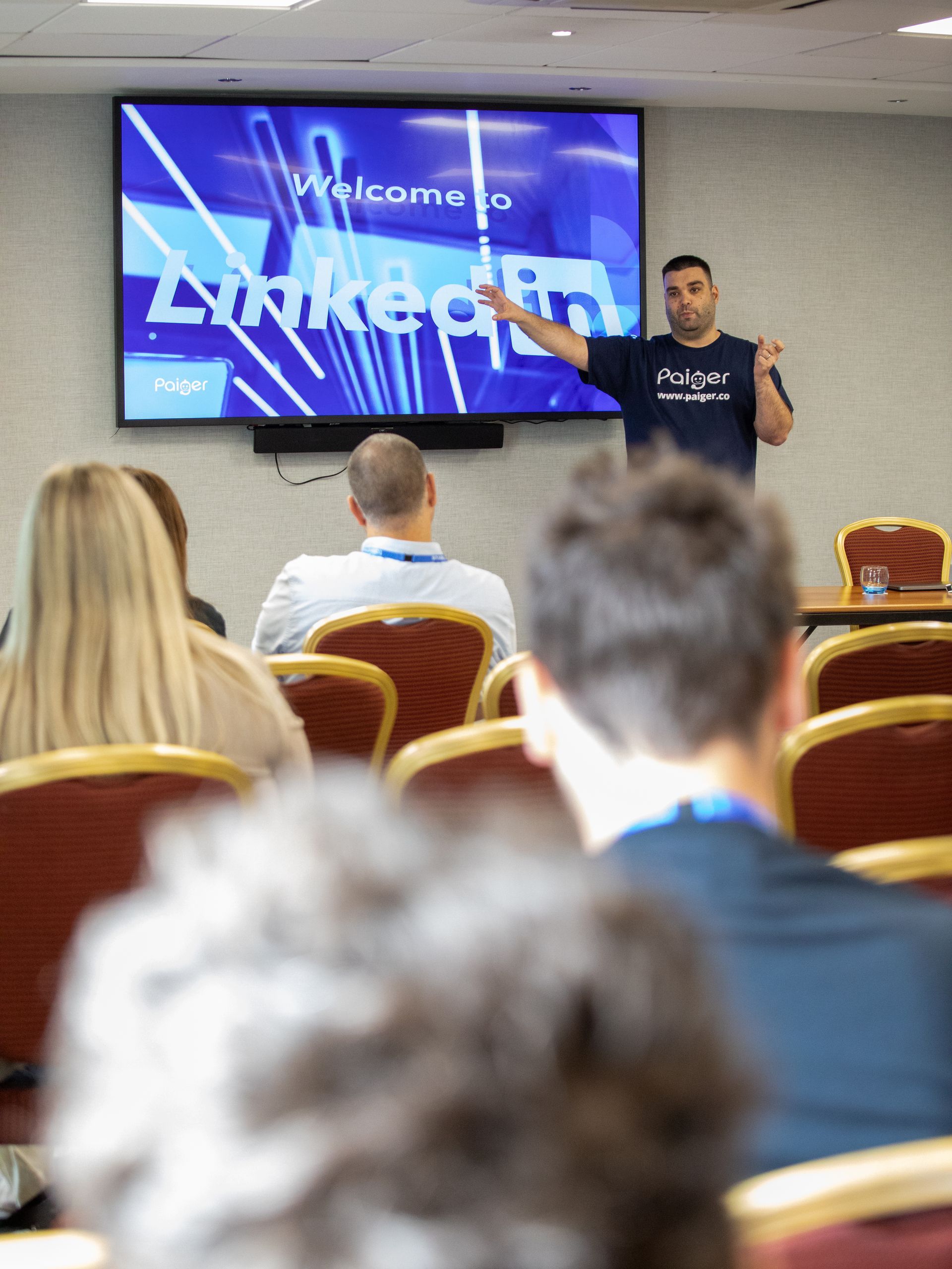 A man is giving a presentation in front of a screen that says welcome to linkedin