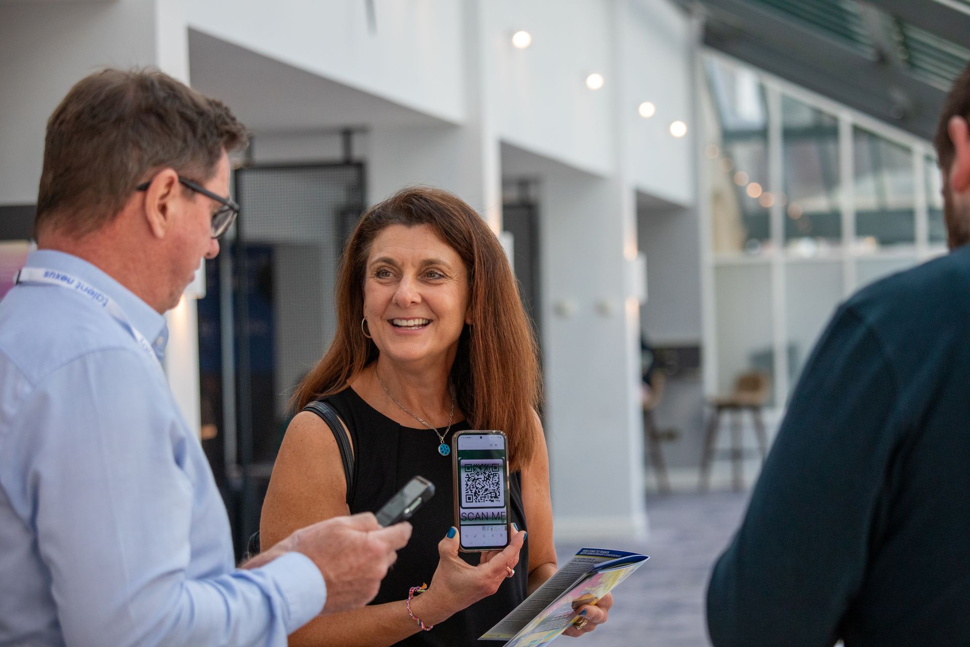 A woman is holding a cell phone while standing next to a man.