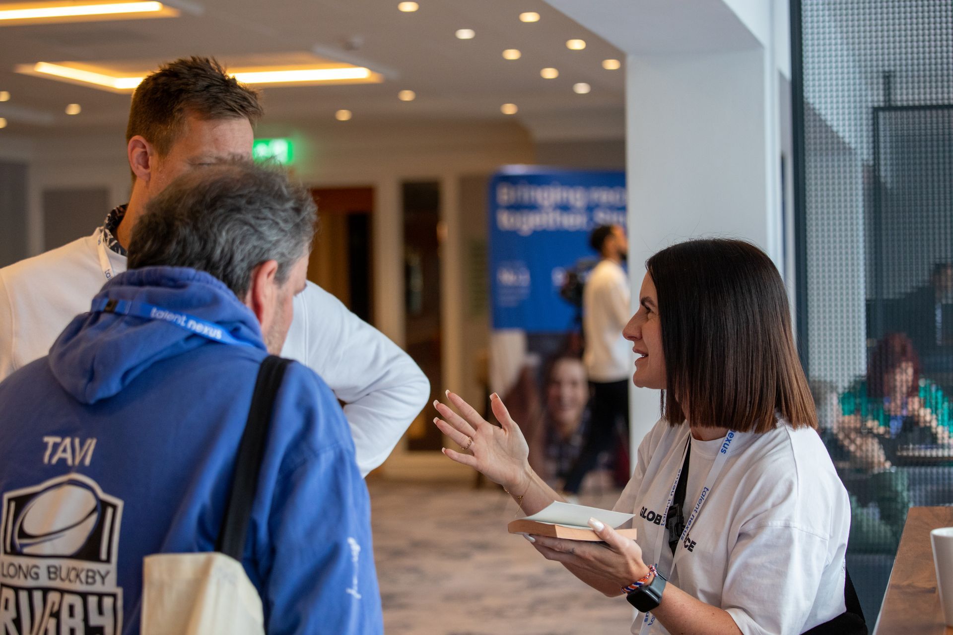 A woman is talking to two men in a room.