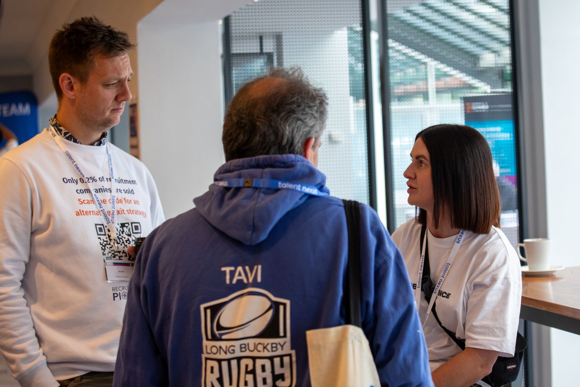 A man in a blue hoodie is talking to a woman in a white shirt.