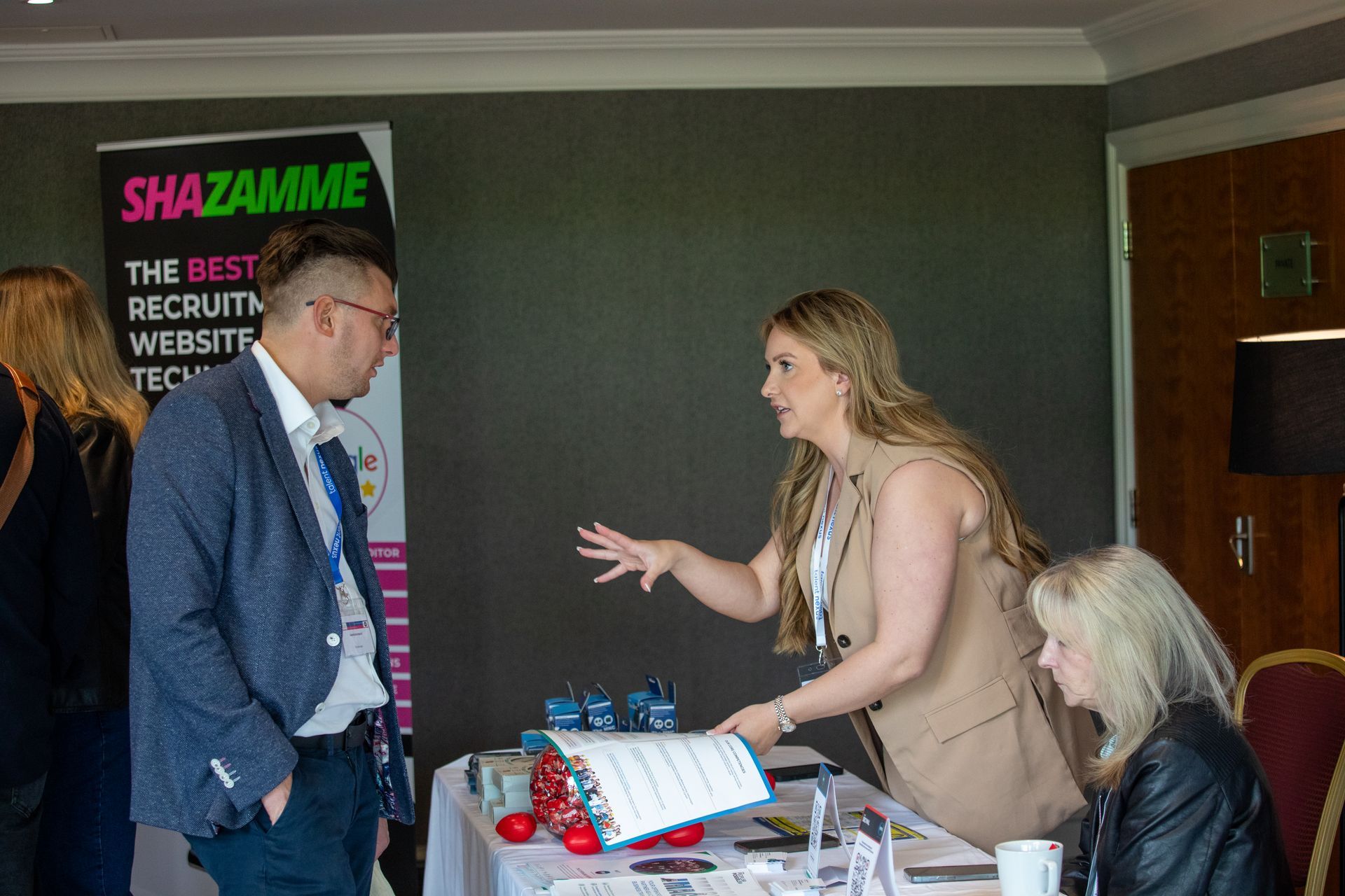 A group of people are standing around a table at a job fair.