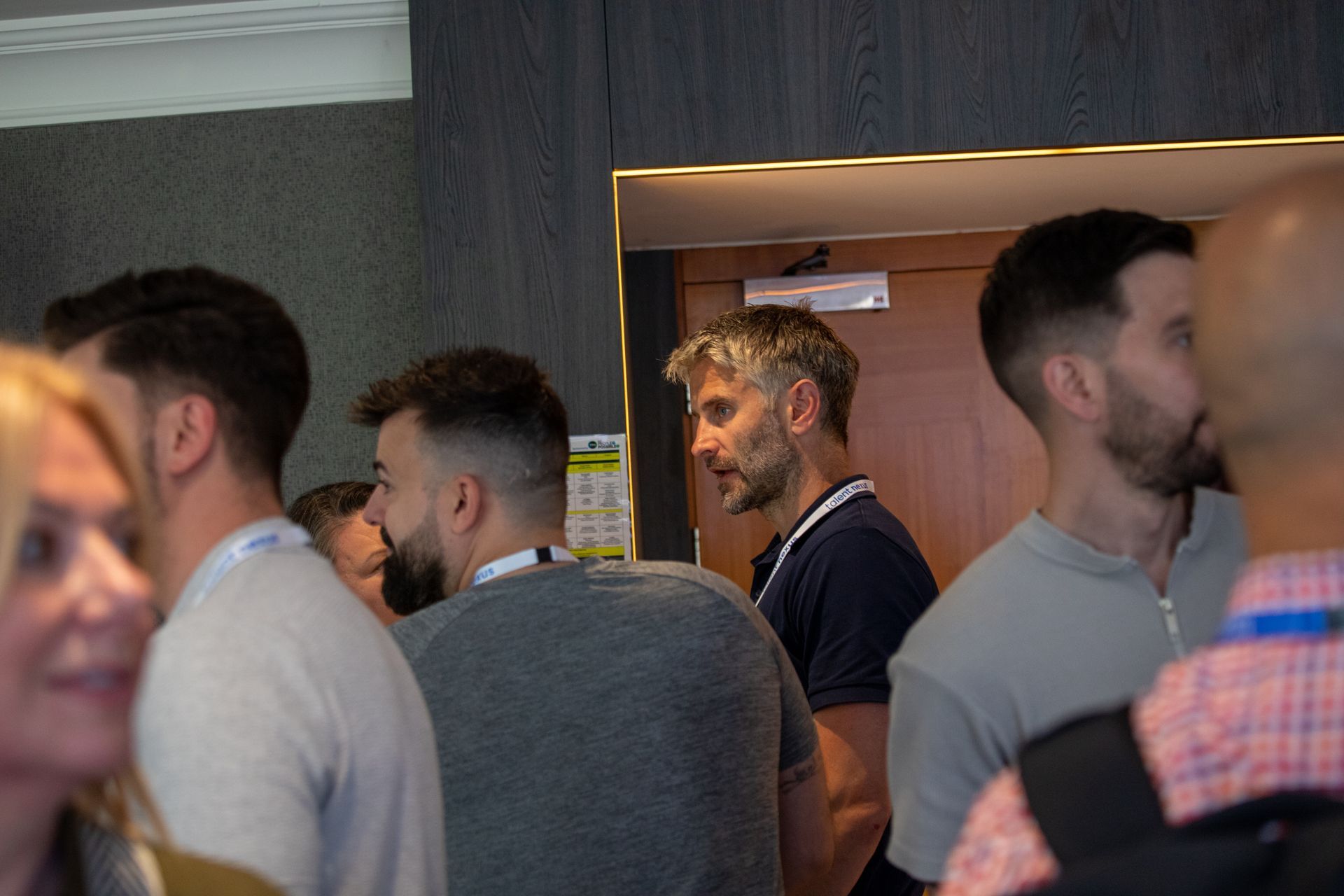 A group of people are standing in a room talking to each other.