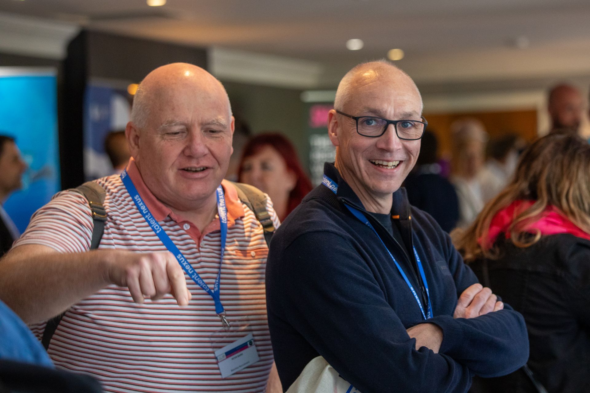 Two men are standing next to each other in a crowded room.