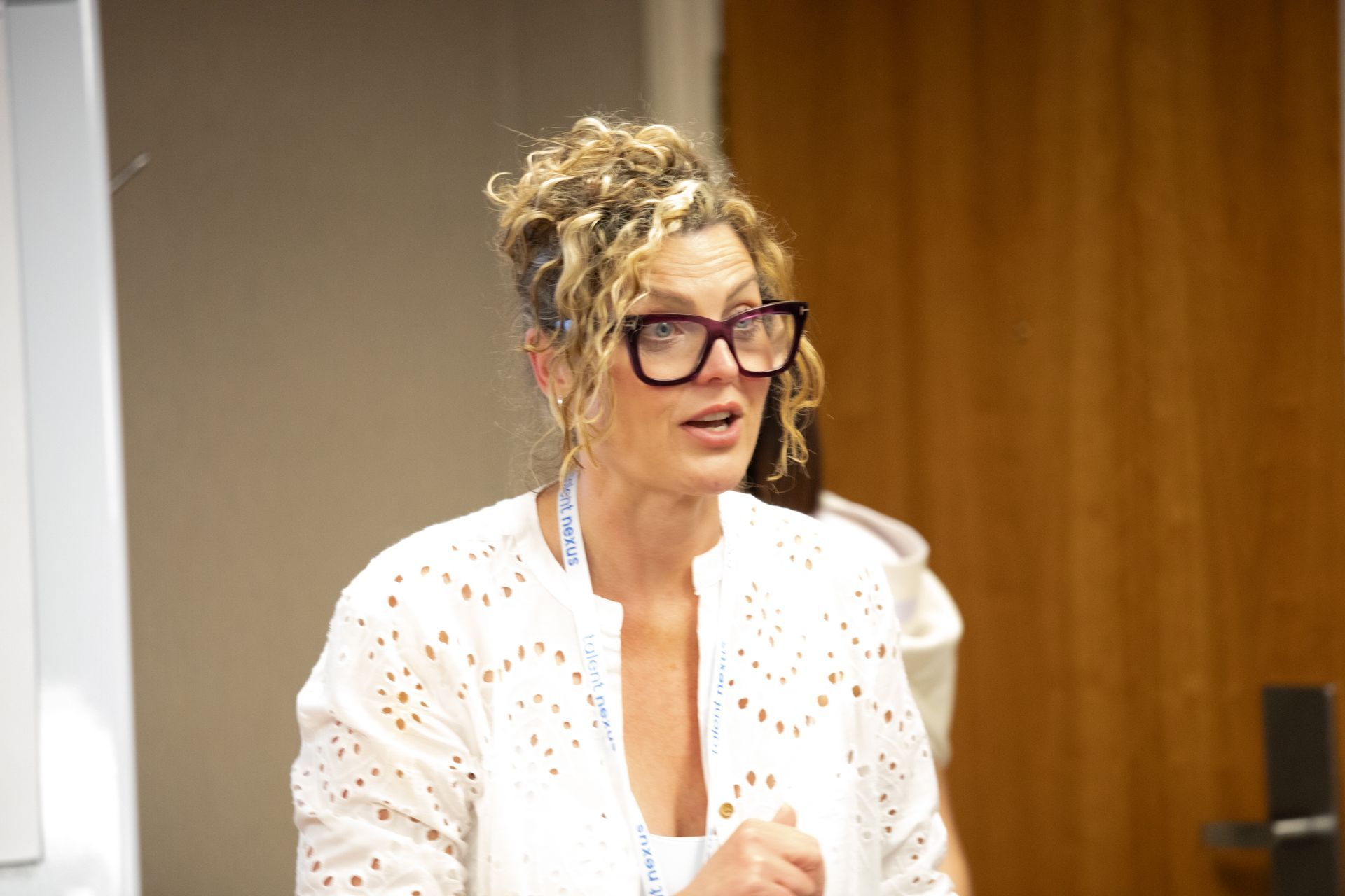 A woman wearing glasses and a white shirt is sitting in front of a door.