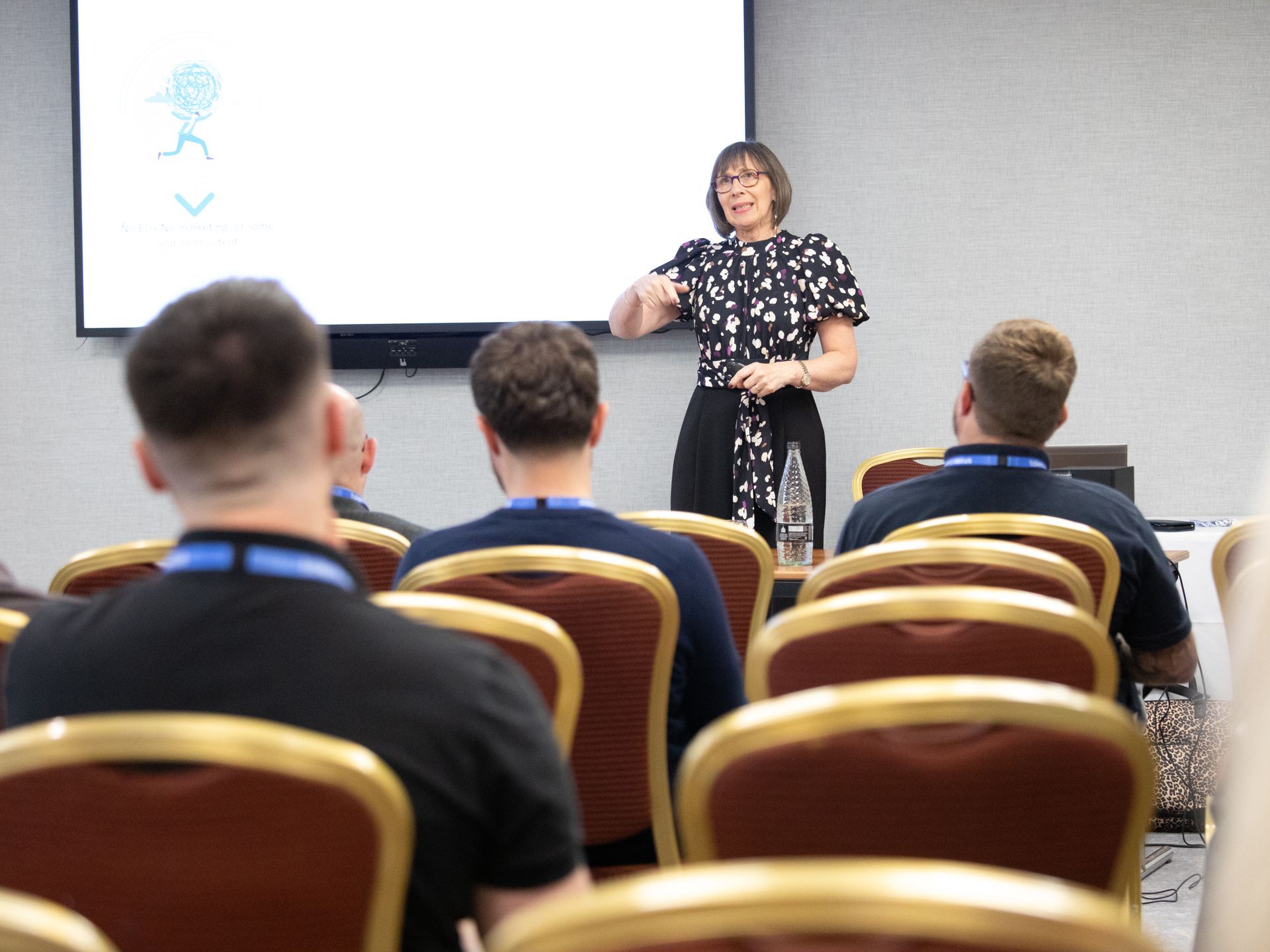 A woman is giving a presentation to a group of people in a conference room.