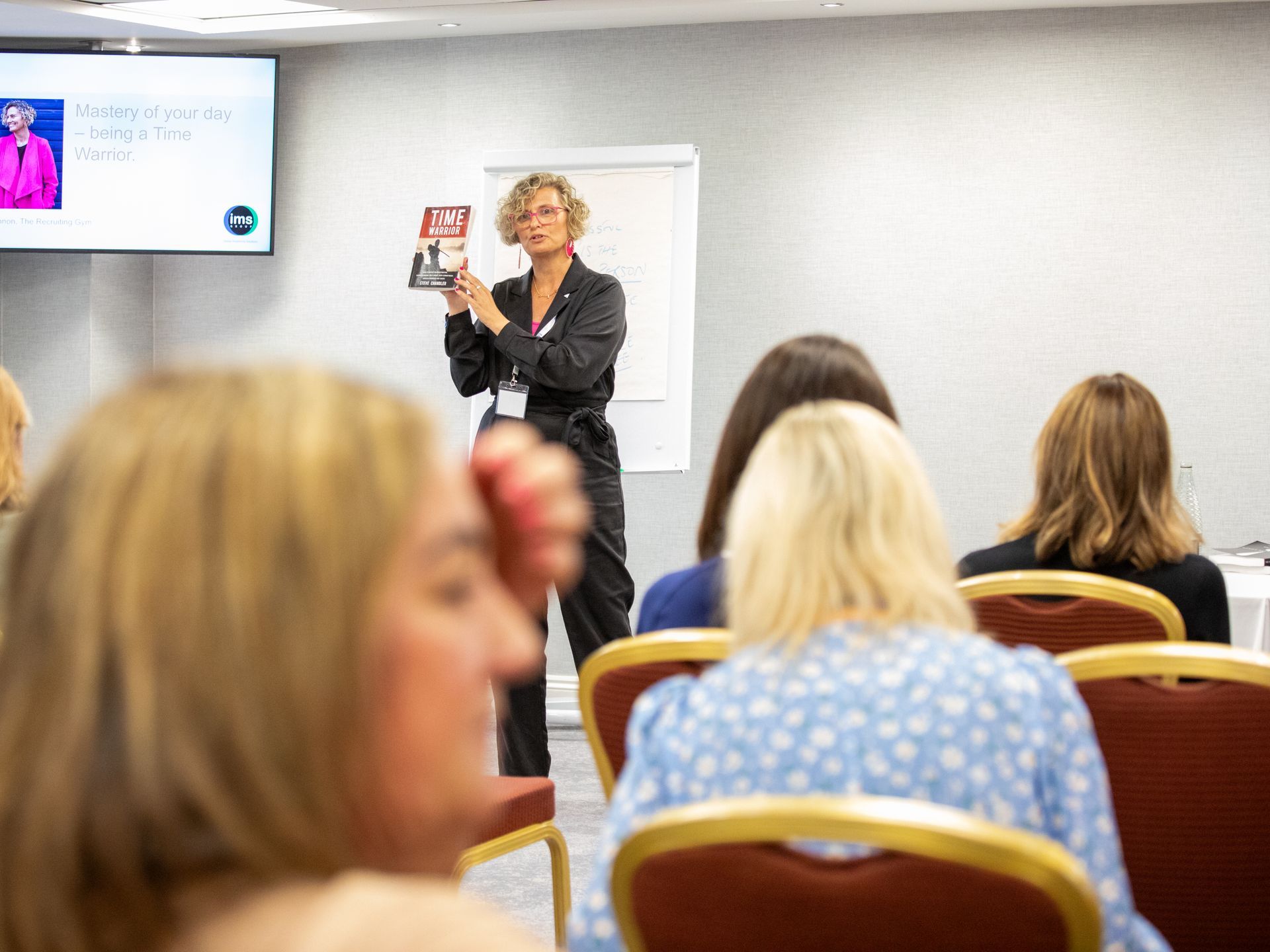 A woman is giving a presentation to a group of women in a conference room.