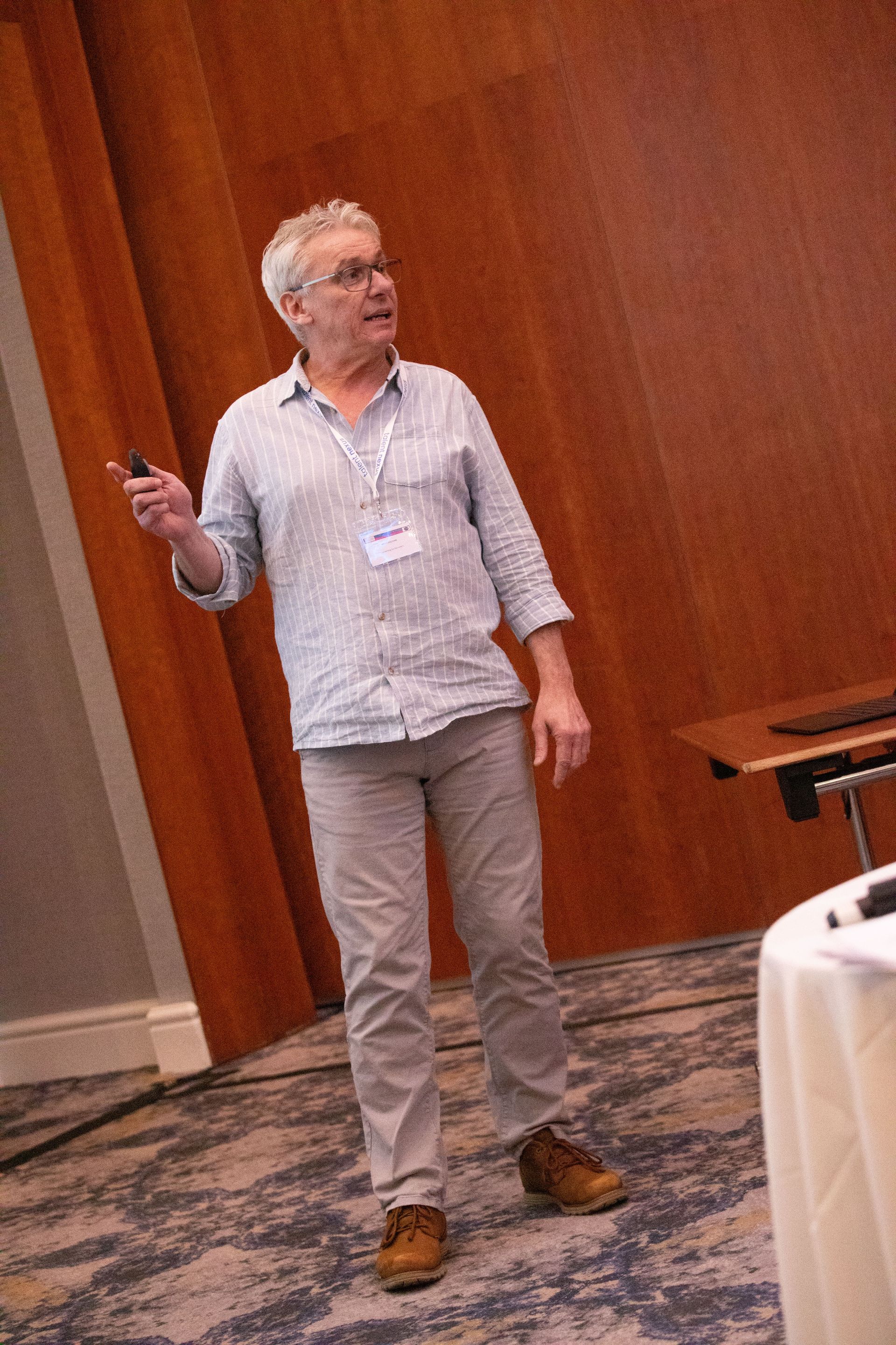 A man is standing in front of a wooden wall holding a cell phone.