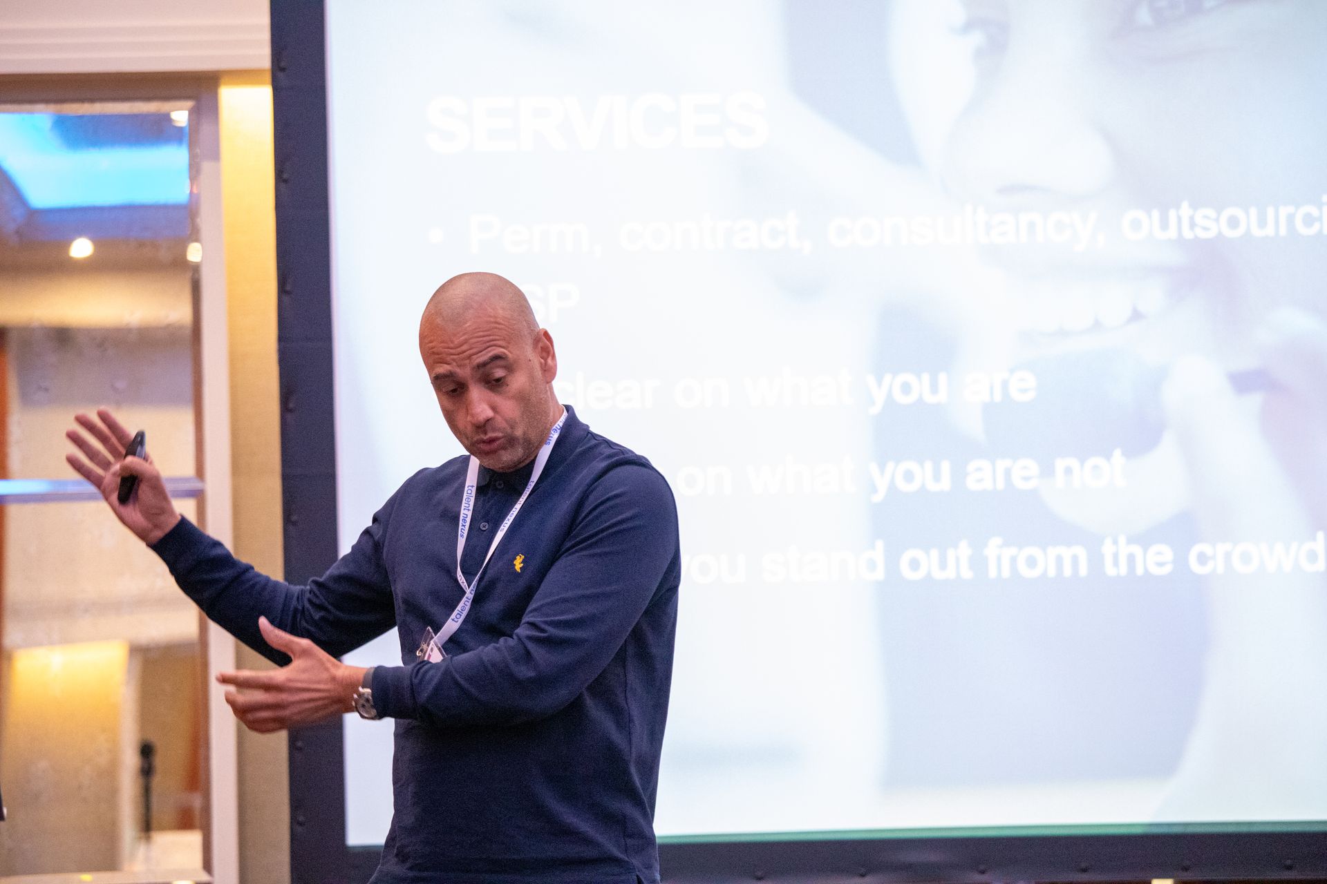 A man is giving a presentation in front of a large screen.