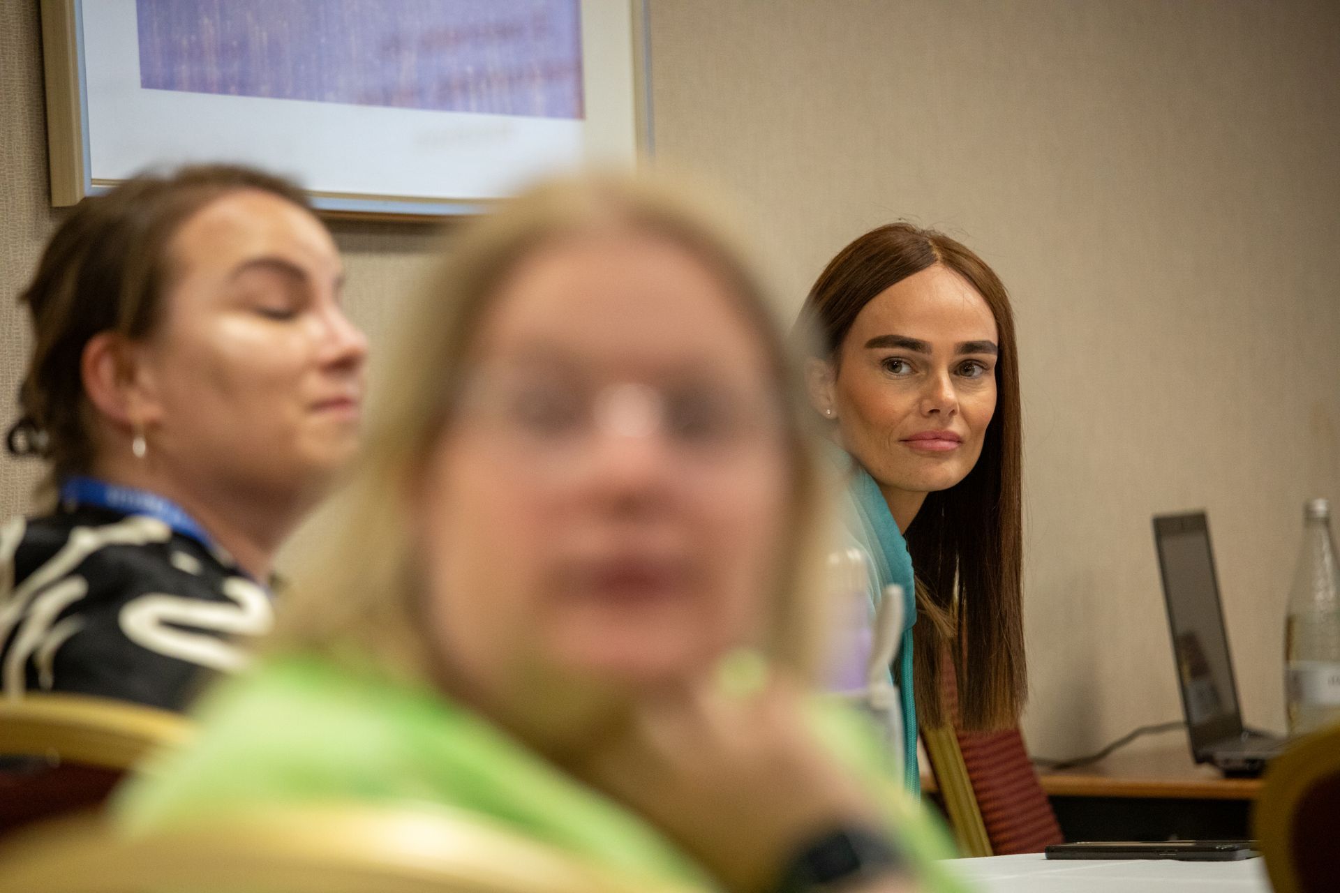 A group of women are sitting at a table in a conference room.