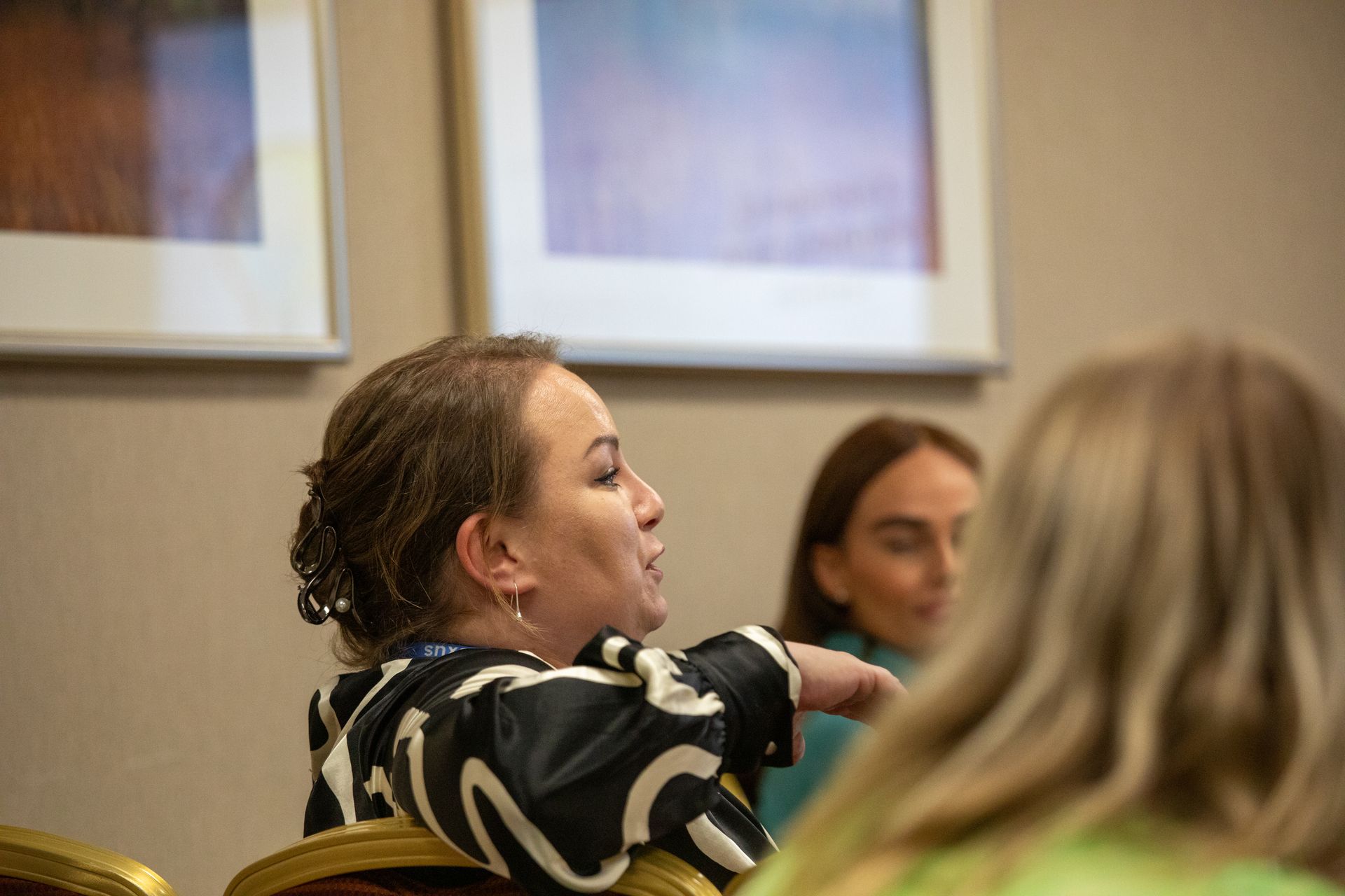 A woman is sitting in a chair talking to another woman.
