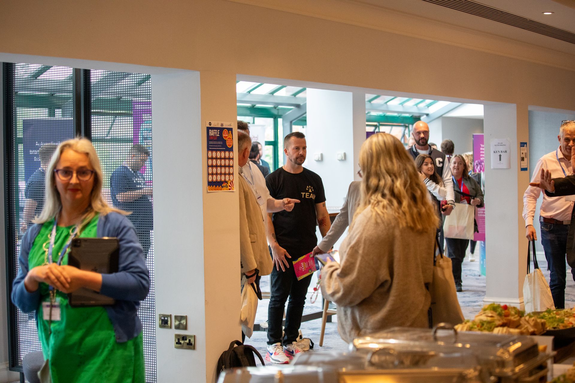 A group of people are standing in a room talking to each other.