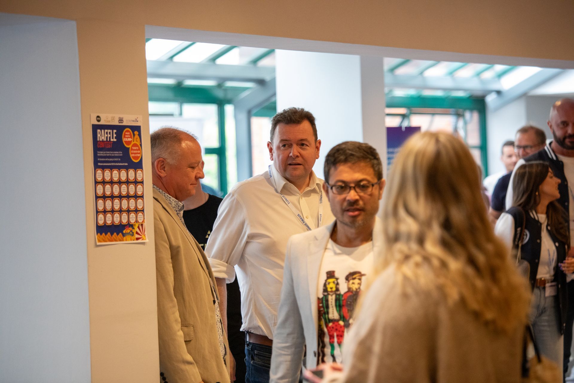 A group of people are standing in a room talking to each other.
