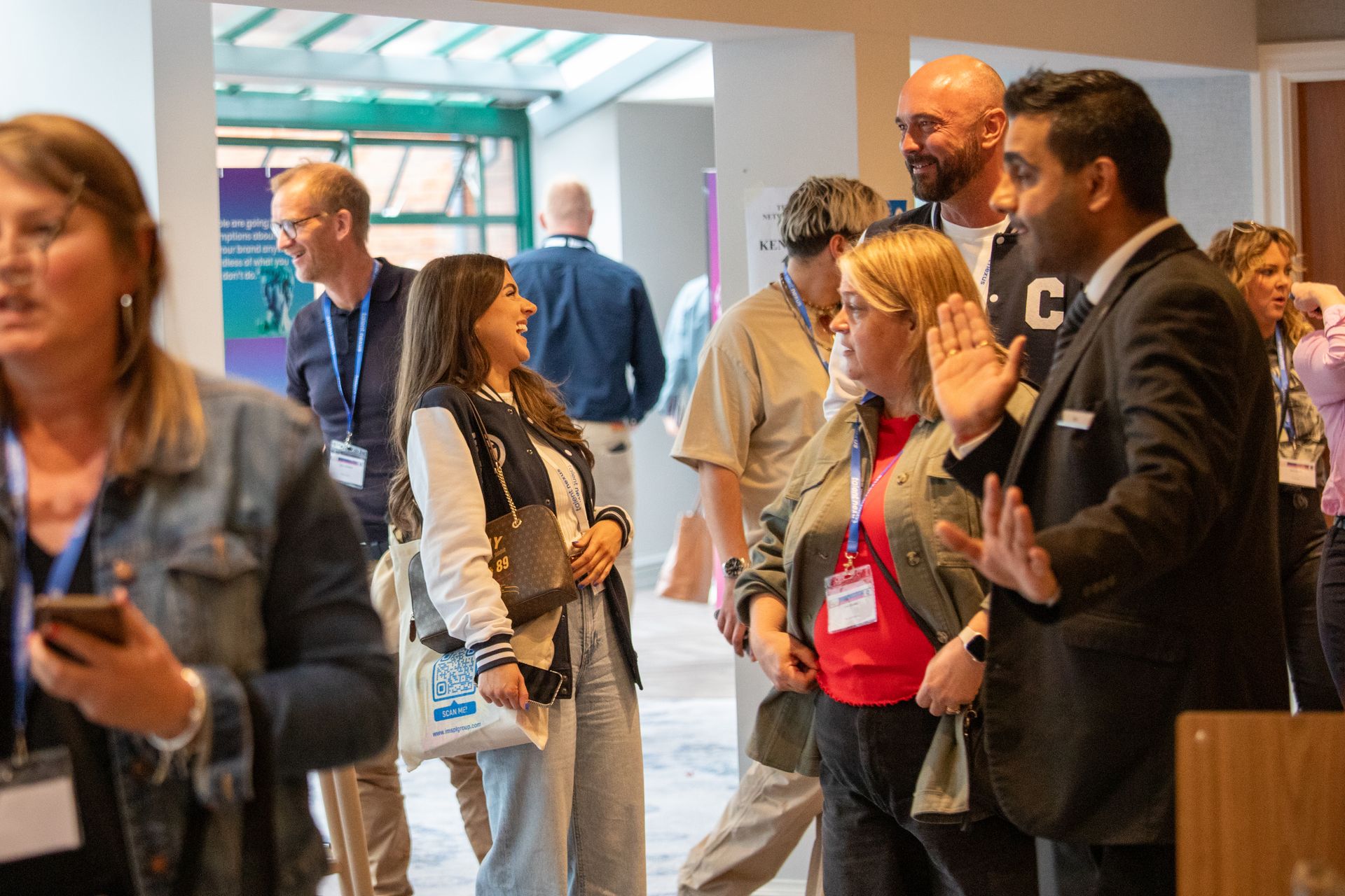 A group of people are standing in a hallway talking to each other.