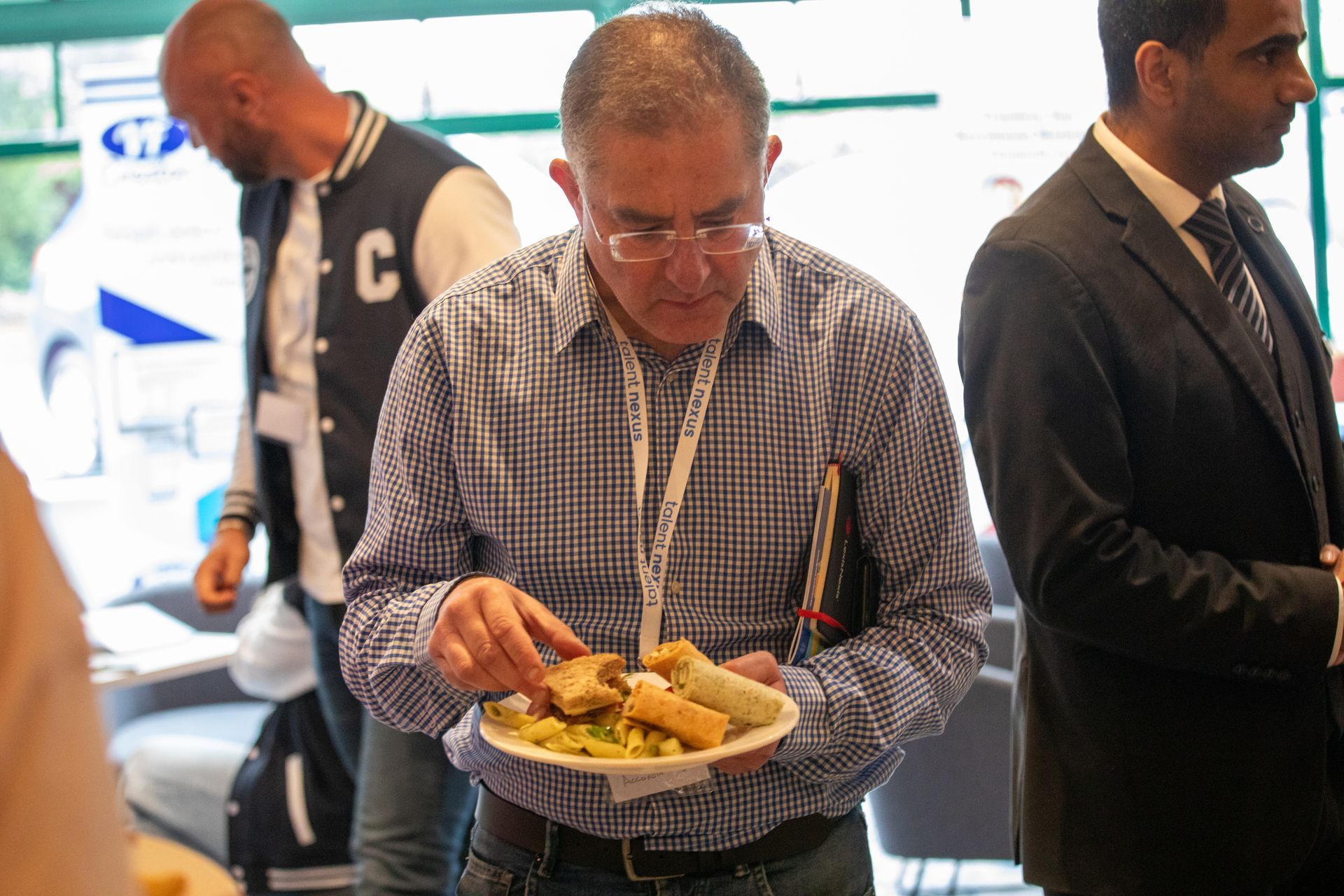 A man in a plaid shirt is holding a plate of food.
