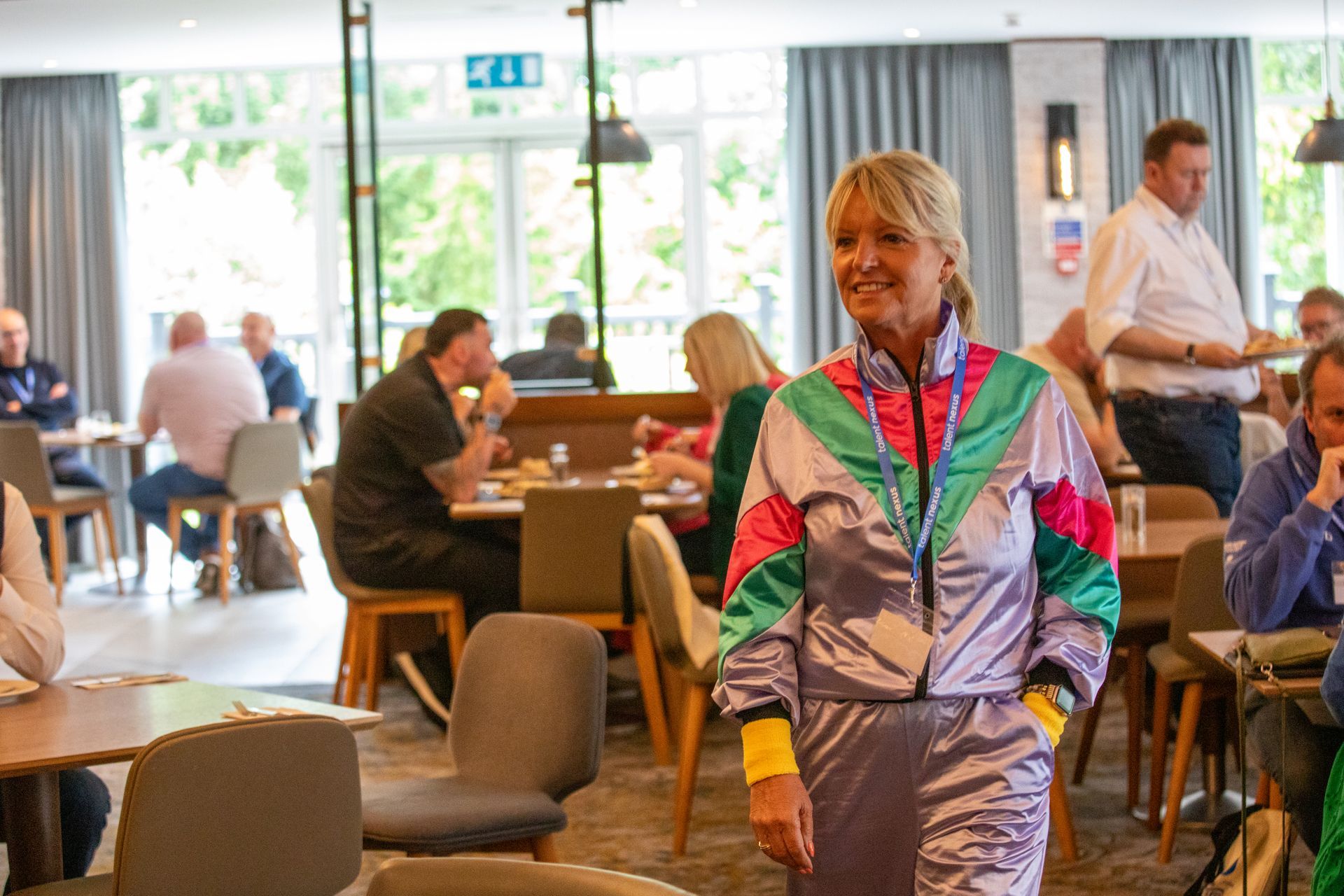 A woman in a colorful jacket is standing in a restaurant.