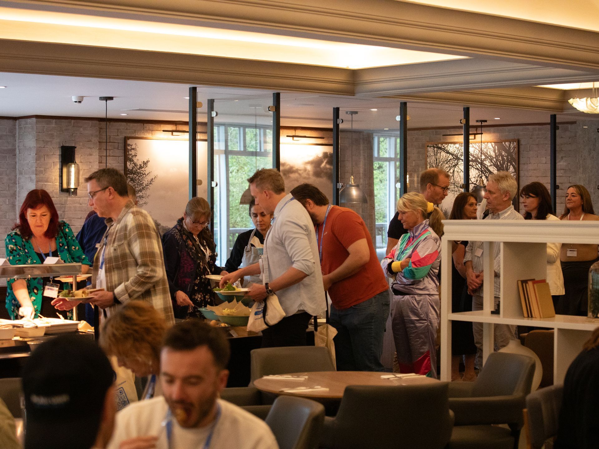 A group of people are standing around tables in a restaurant.