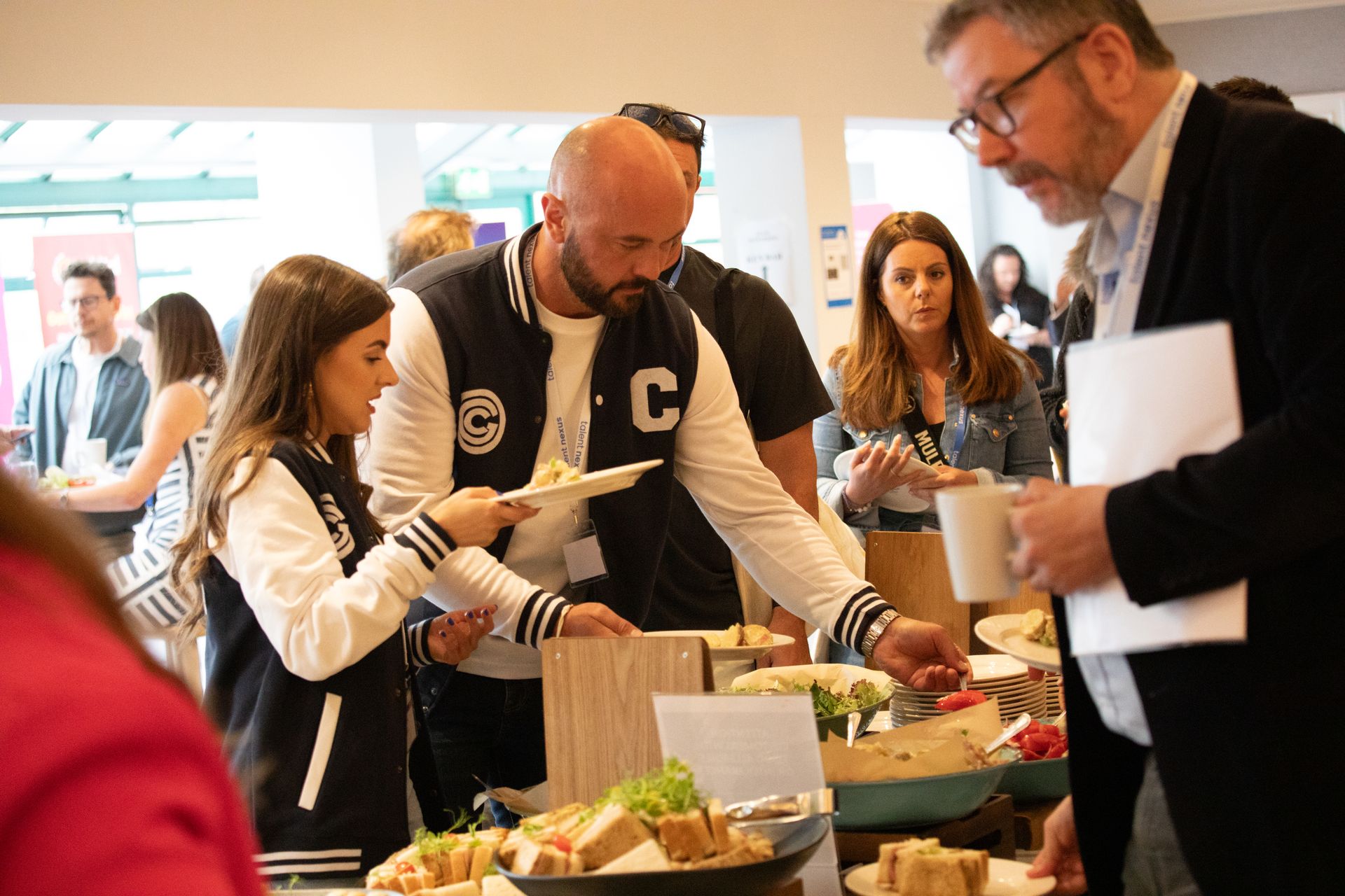 A group of people are standing around a table eating food.