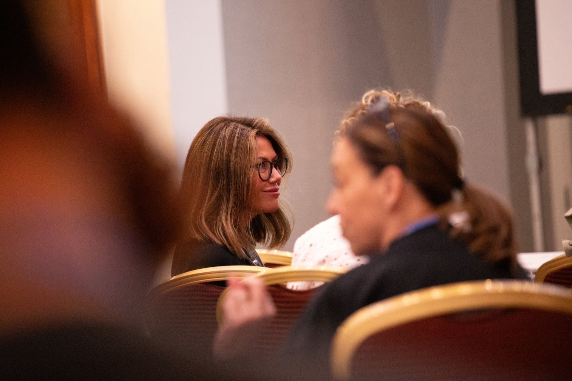 A group of women are sitting in chairs at a conference.