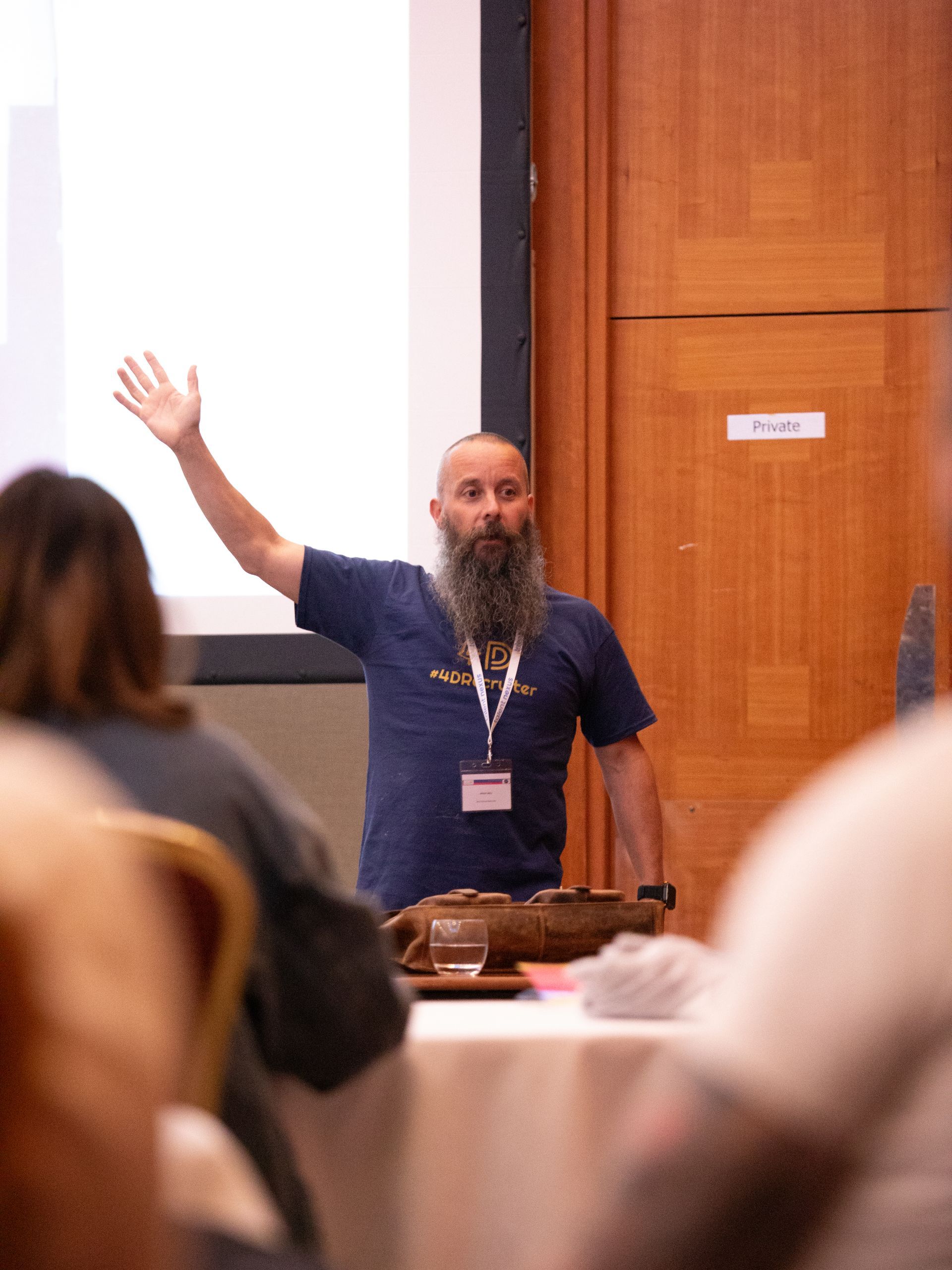 A man with a beard is giving a presentation to a group of people
