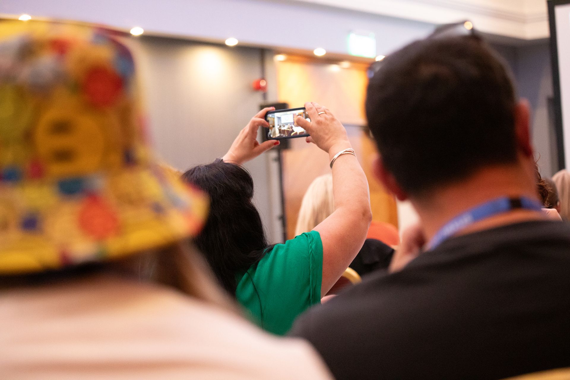 A group of people are sitting in chairs taking pictures with their cell phones.