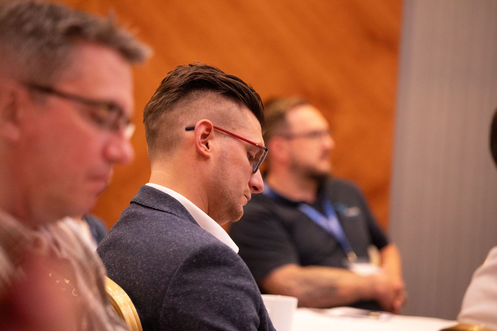 A man wearing glasses is sitting at a table with other people.