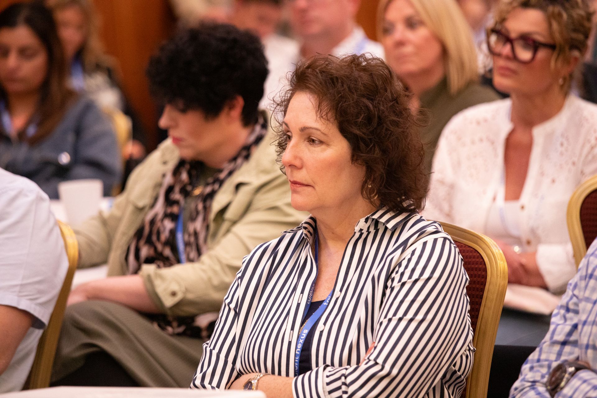 A woman in a striped shirt is sitting in a crowd of people.