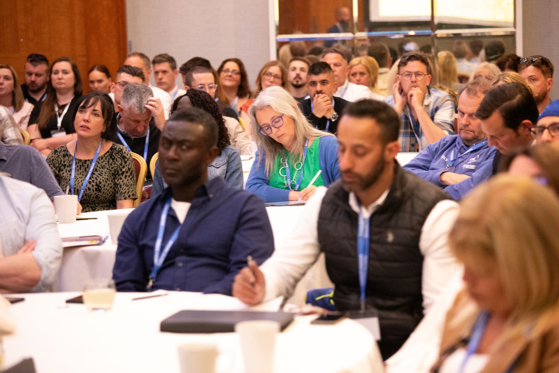 A large group of people are sitting at tables in a conference room.