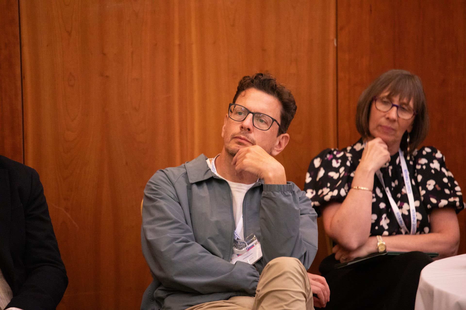 A man and a woman are sitting at a table with their hands on their chins.