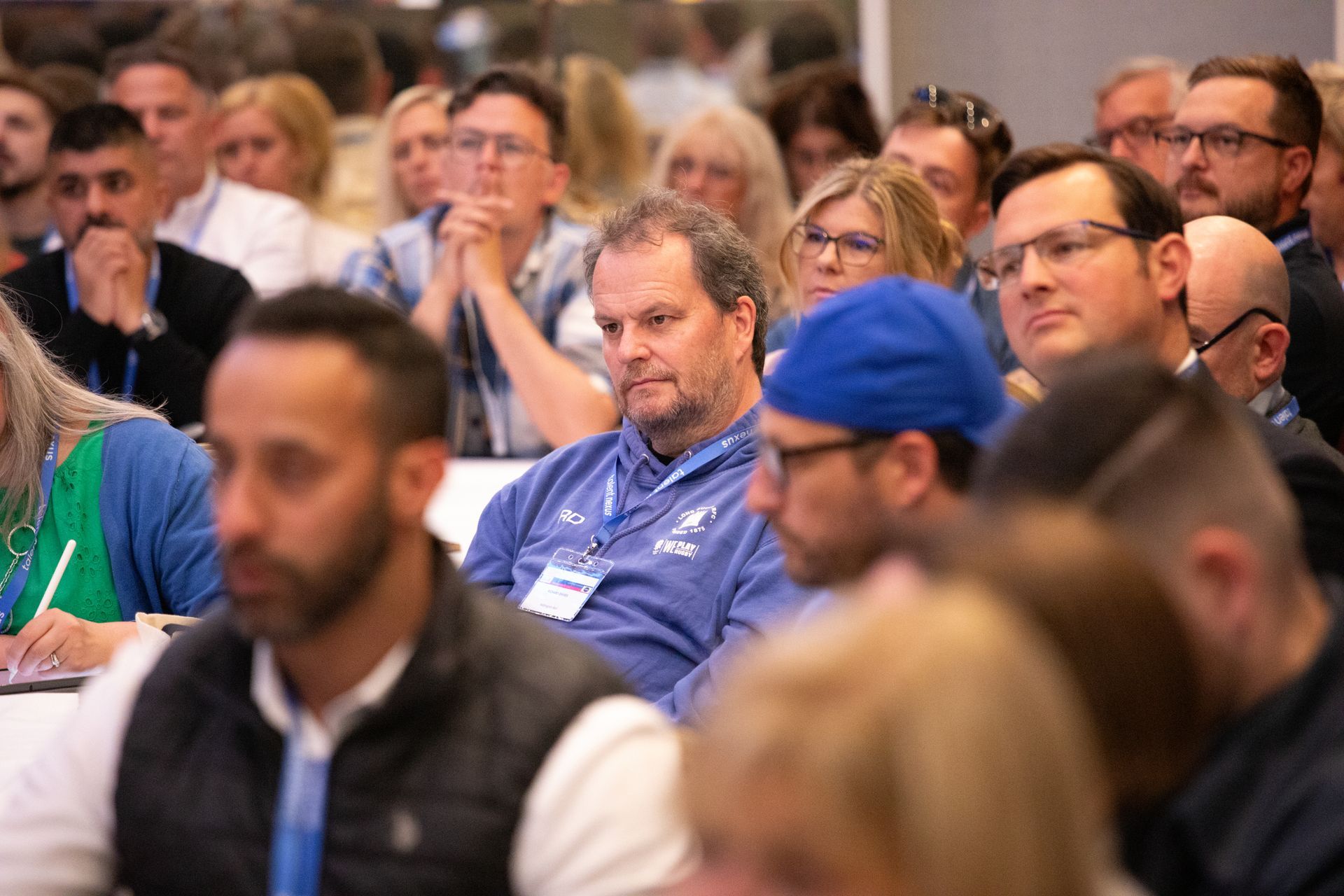 A large group of people are sitting in a room watching a presentation.