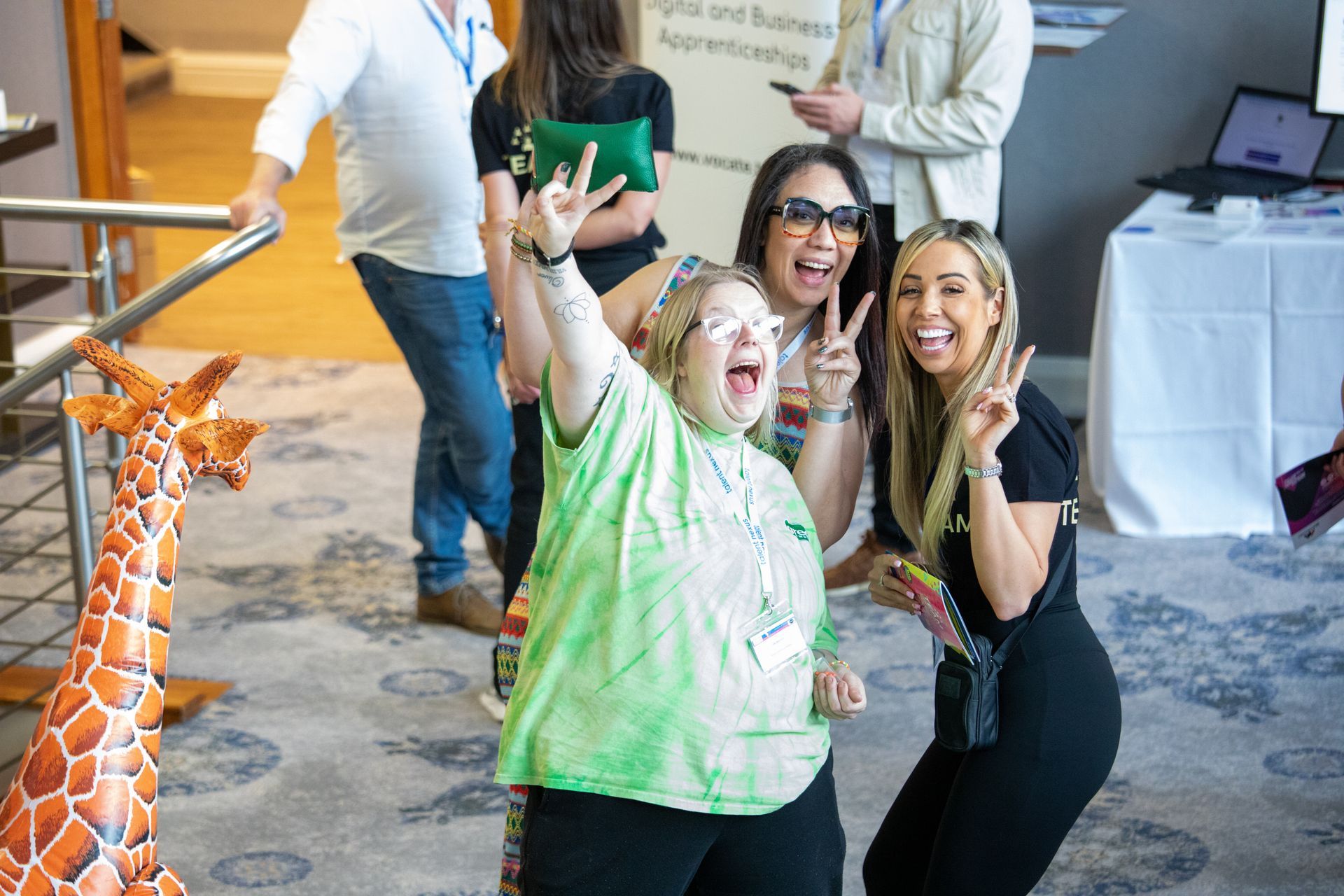 A group of women are posing for a picture in front of a stuffed giraffe.