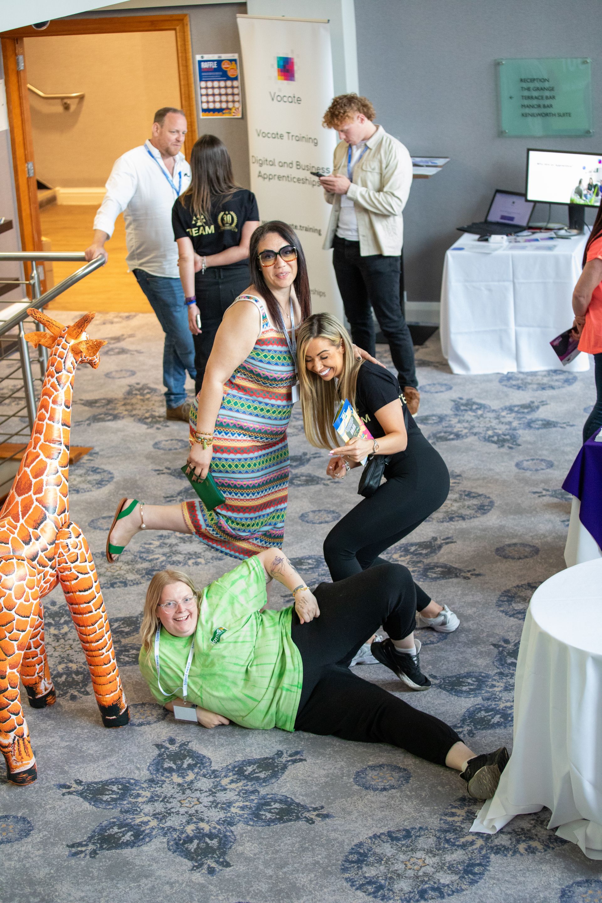 A group of people are playing with a stuffed giraffe in a room.