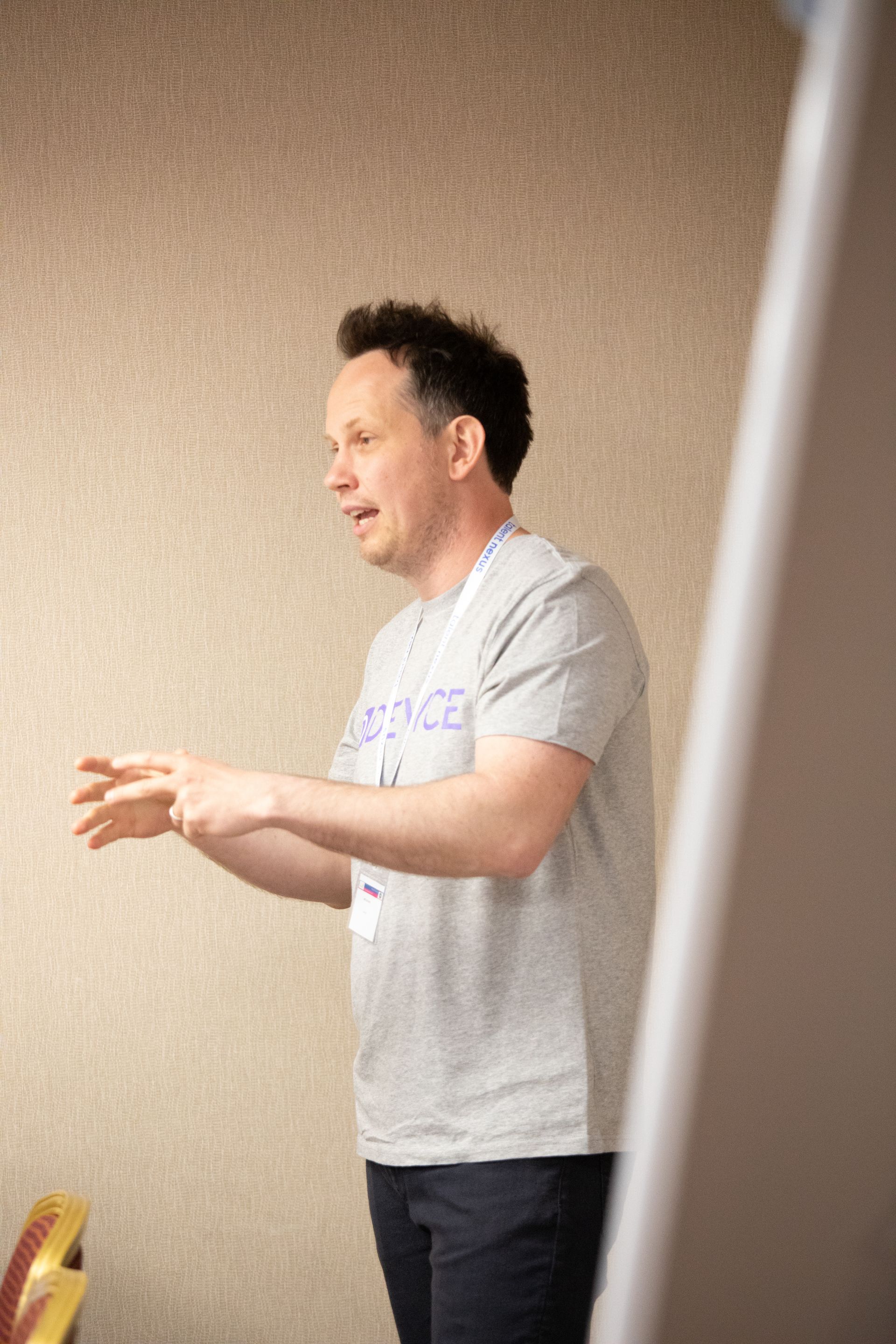 A man in a gray shirt is standing in front of a white board.