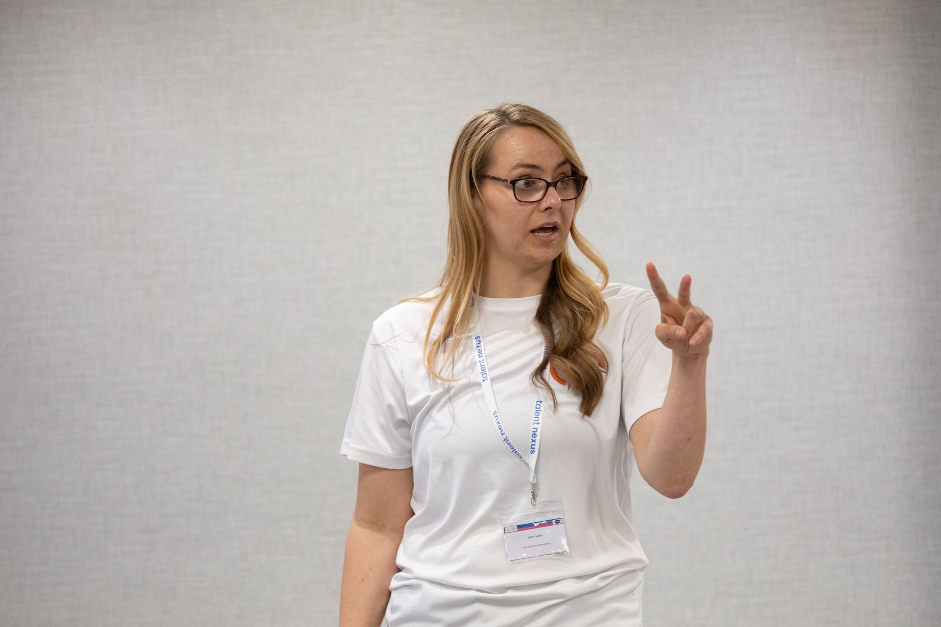 A woman wearing glasses and a white shirt is giving a presentation.
